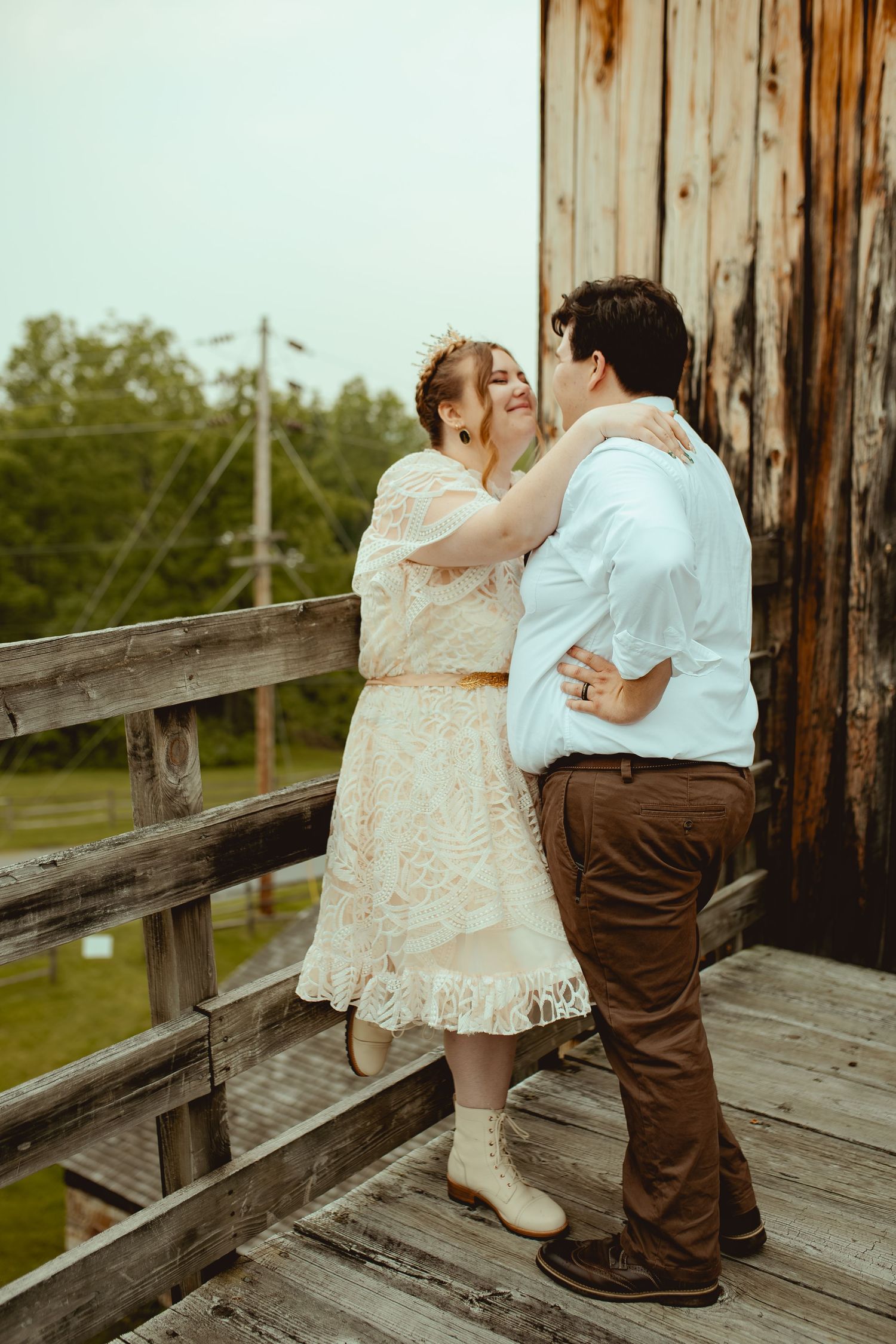 Two people share a tender moment on a rustic wooden deck overlooking nature.