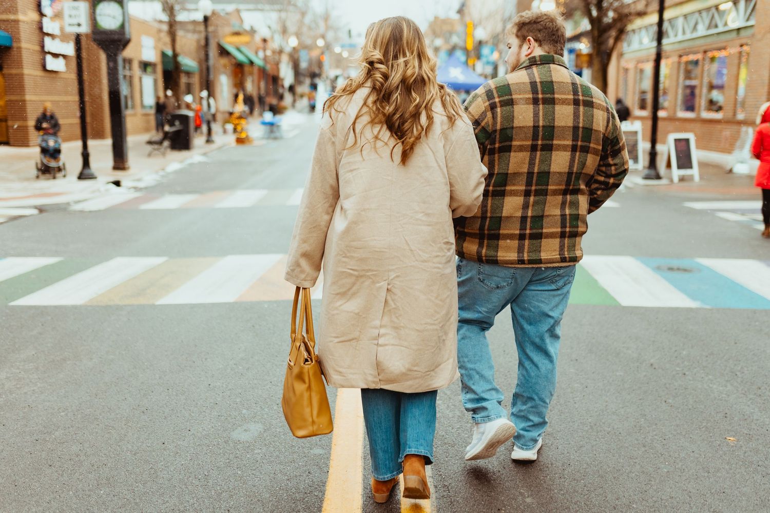 Couple walking together on a city street during autumn wearing casual outfits.