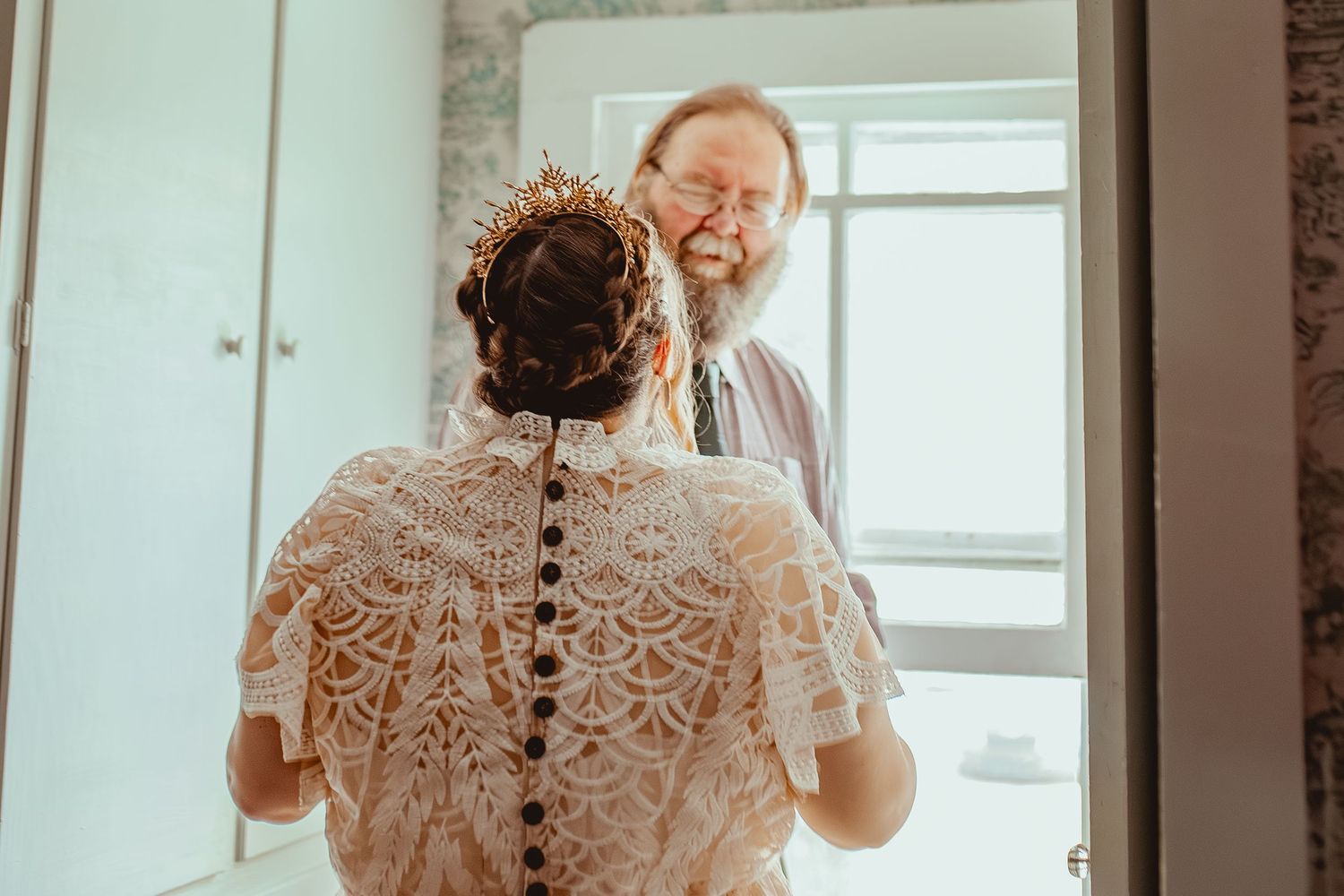 A heartwarming moment captured during a wedding as someone reacts emotionally to seeing a bride in a vintage-style lace dress.