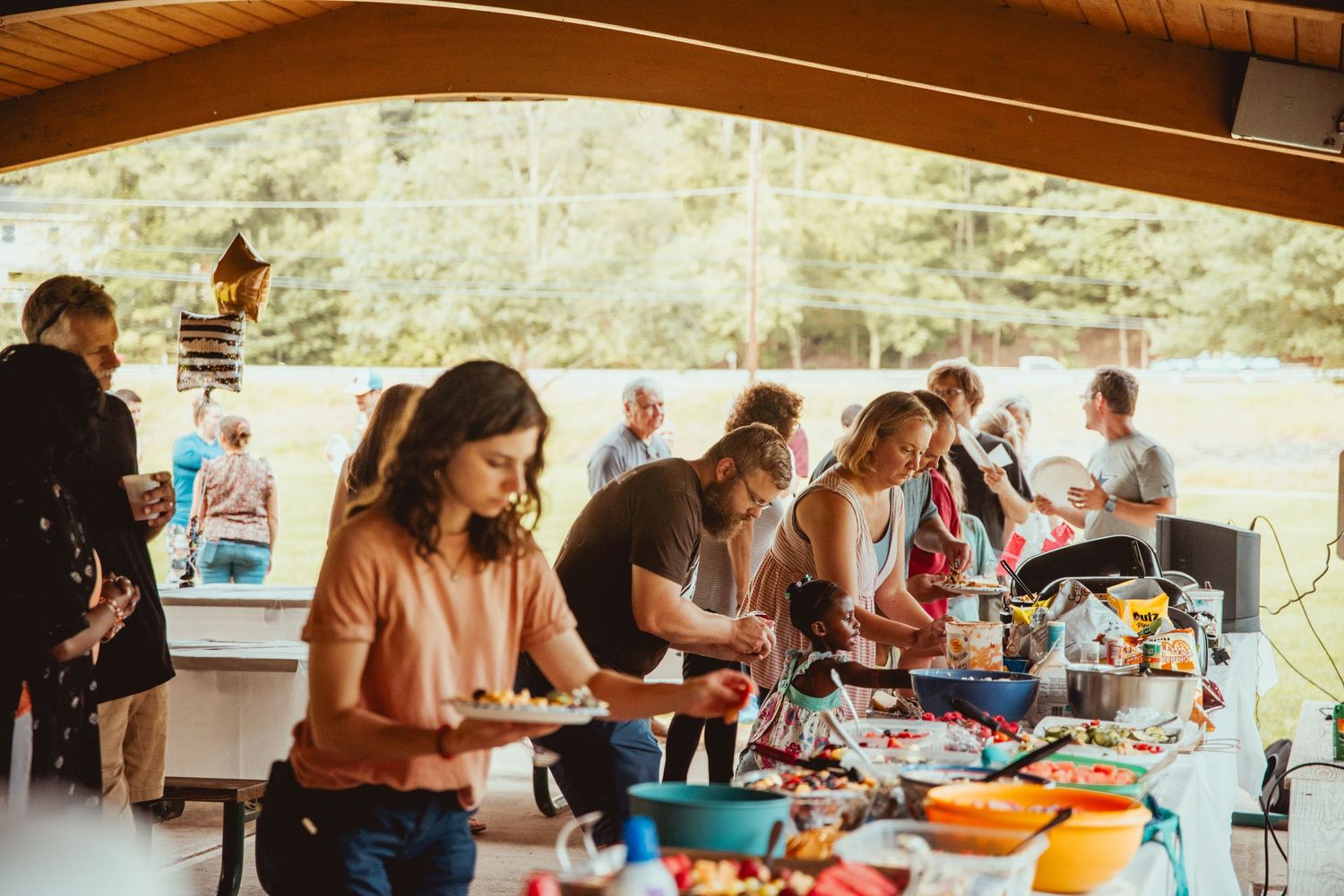 People gathered around tables enjoying a meal together in a rustic dining area with wooden beams and stone walls.