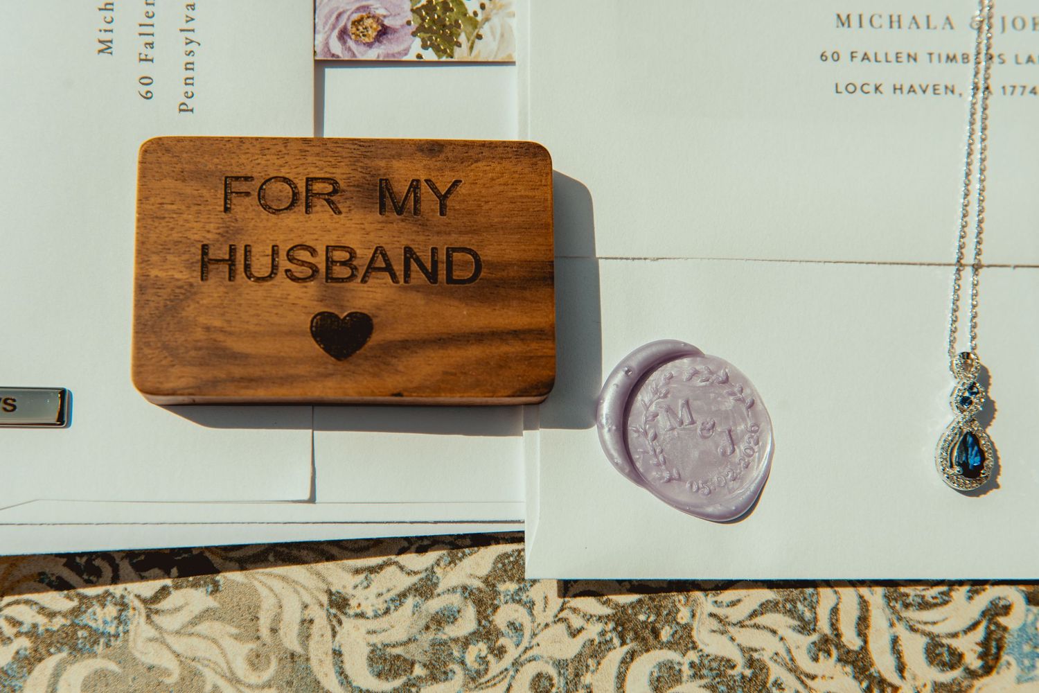 Wooden box engraved with For My Husband and heart, displayed with wax seal, blue gemstone necklace, and wedding stationery.