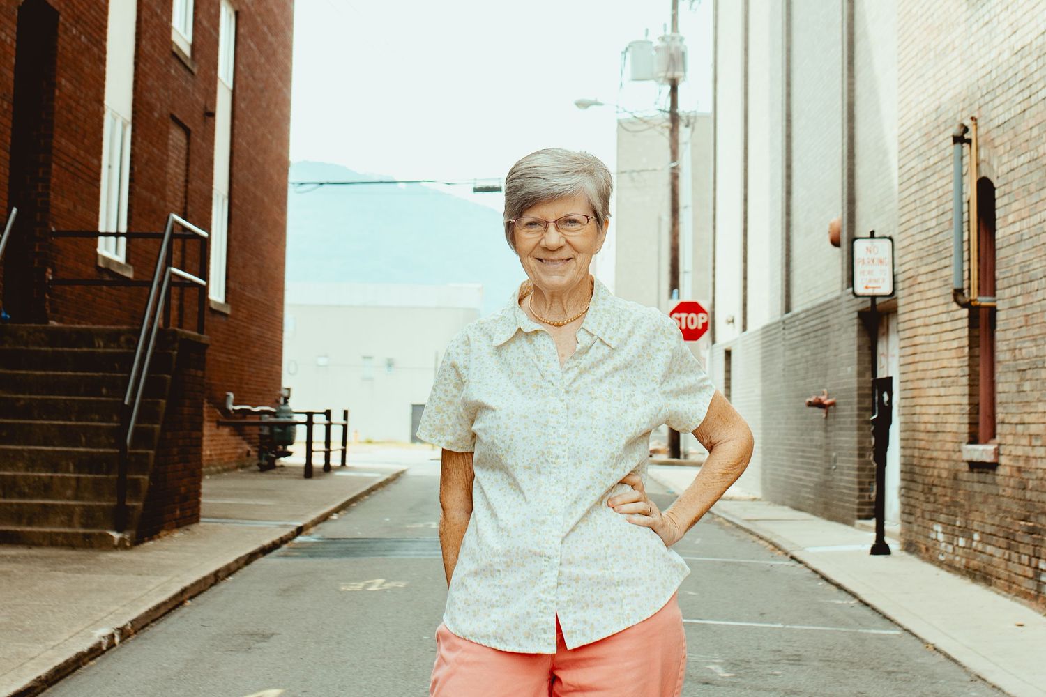 A person in a light colored shirt stands against white walls in an urban alleyway in multiple connected photos.