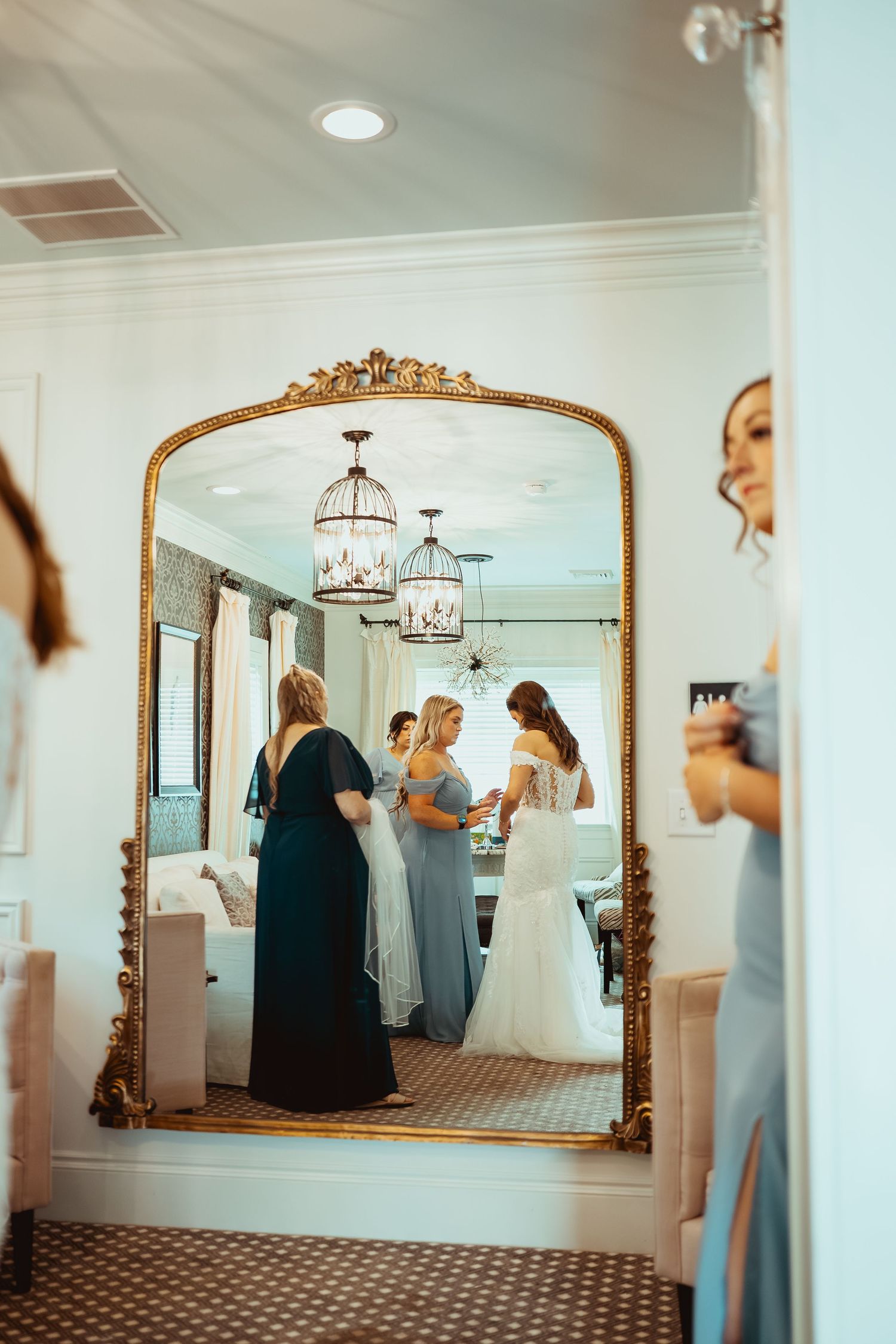 Elegant dressing room with ornate mirrors and chandeliers showing wedding preparations.