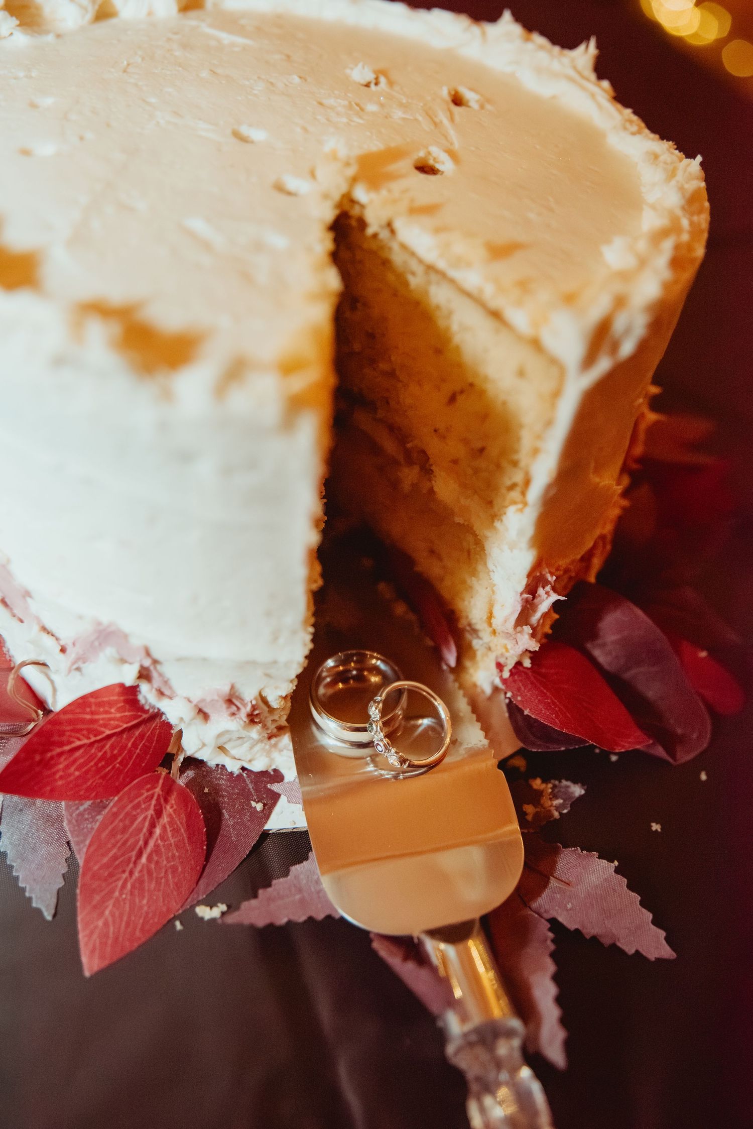 Slices of creamy white cheesecake decorated with red autumn leaves and caramel drizzle on dark background.