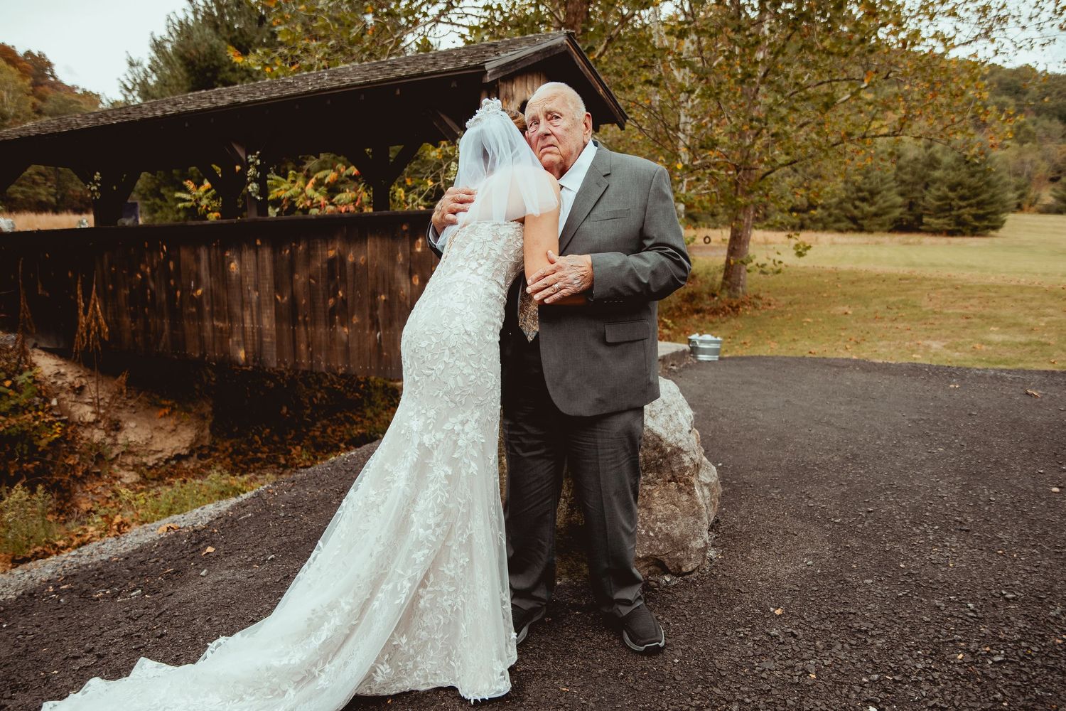 Couple poses together against rustic outdoor backdrop with autumn foliage.