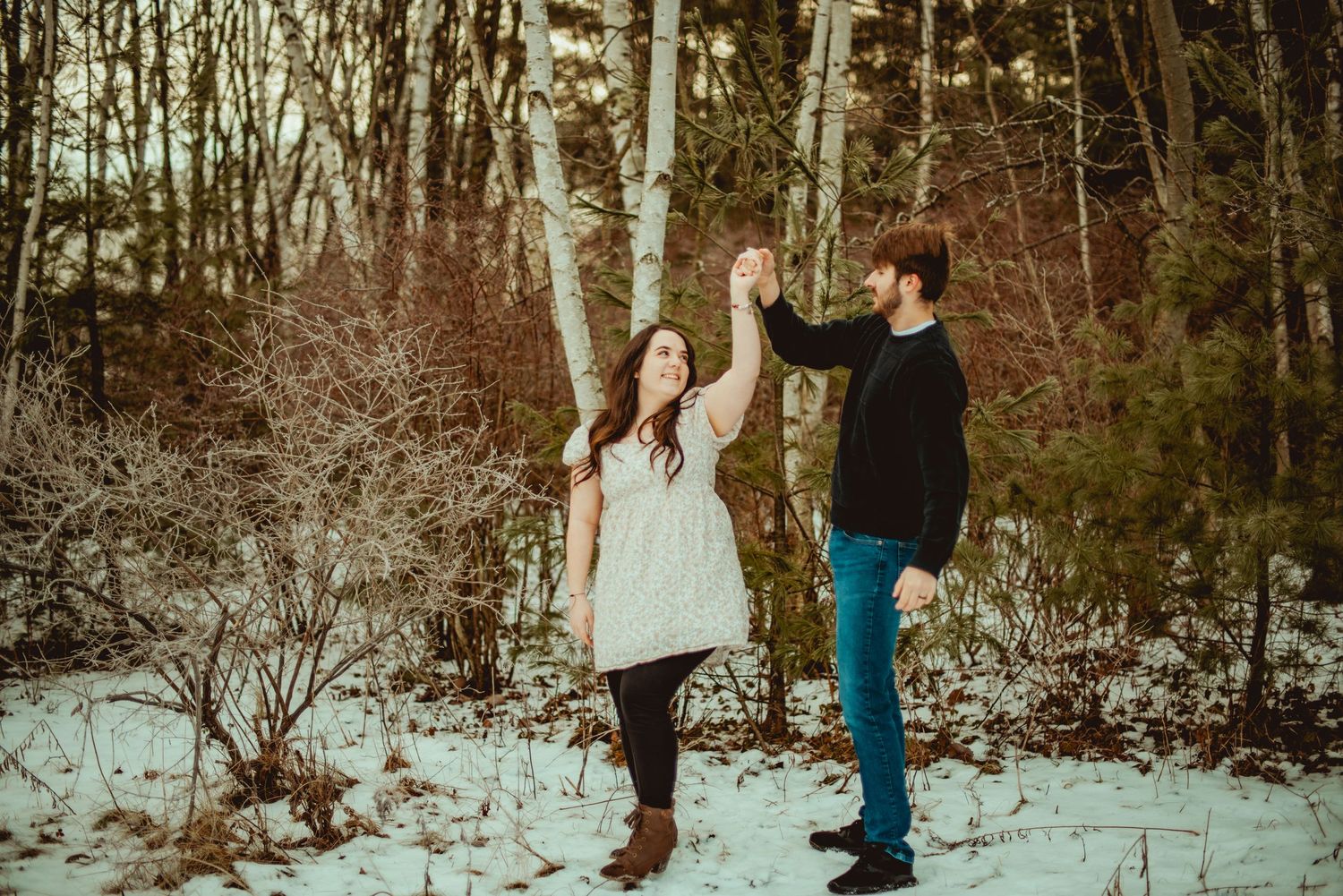A couple embraces in a snowy winter landscape during a romantic outdoor photoshoot.