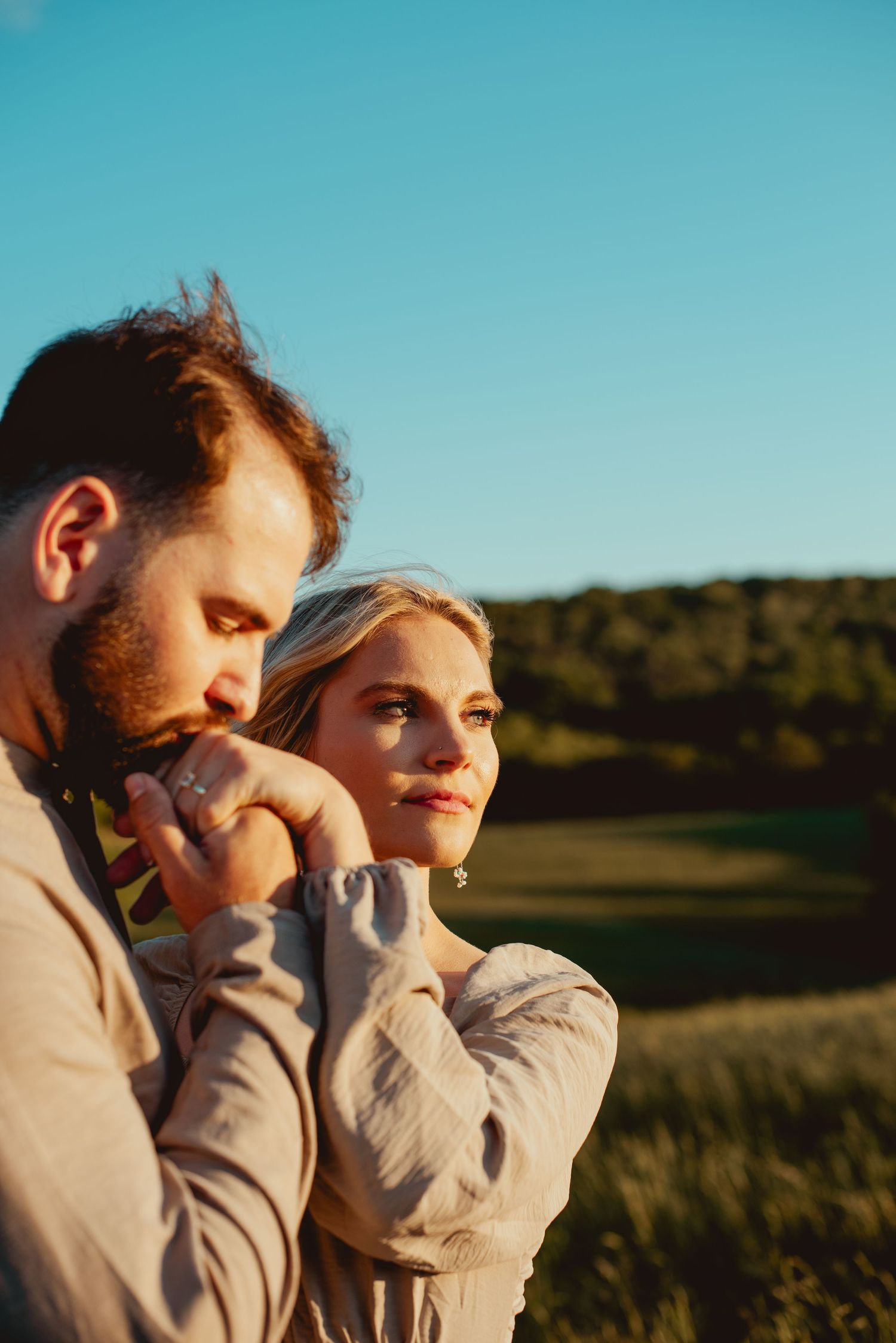 A couple shares an intimate moment at sunset in a natural outdoor setting.