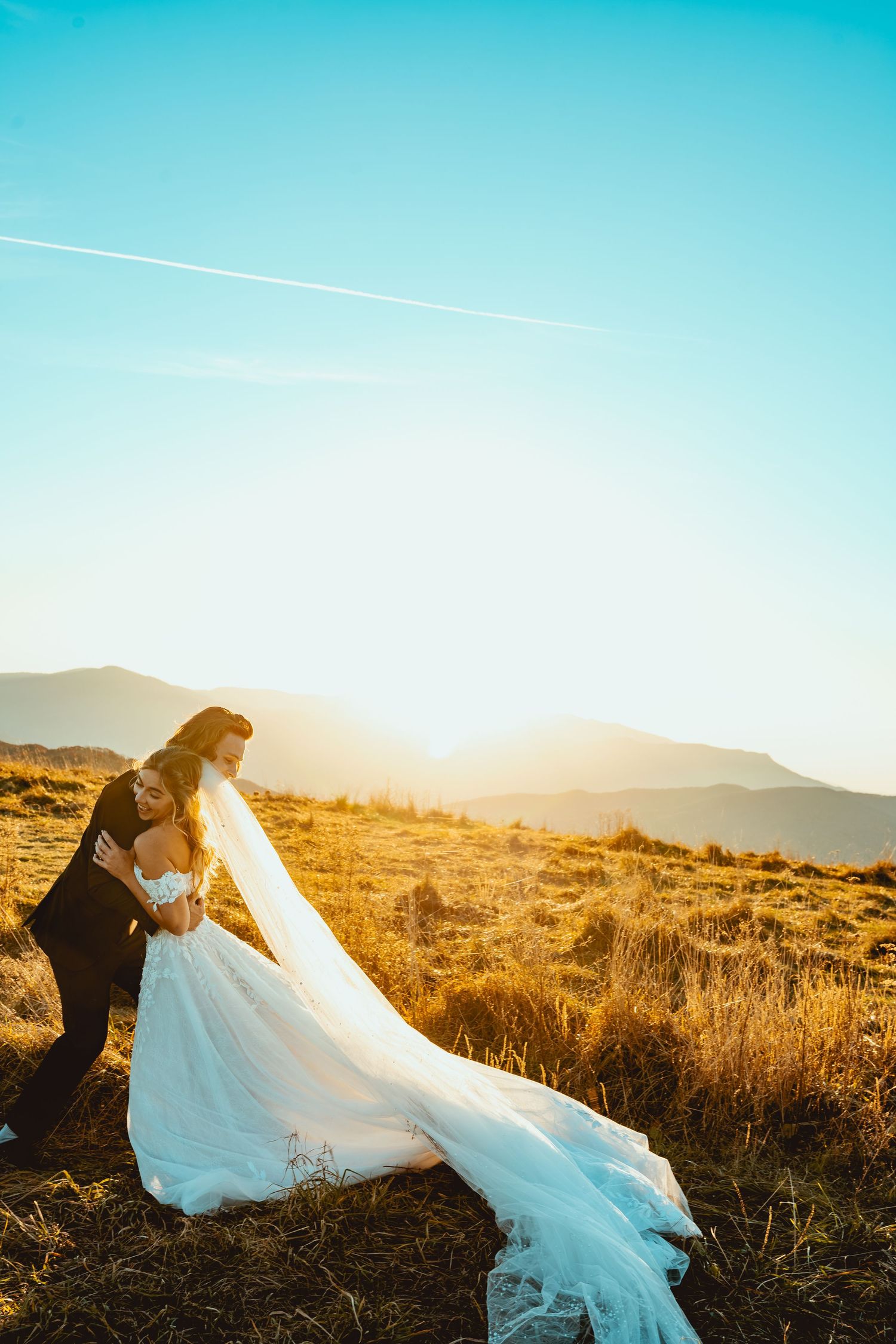 A romantic wedding photoshoot in a desert landscape during sunset.
