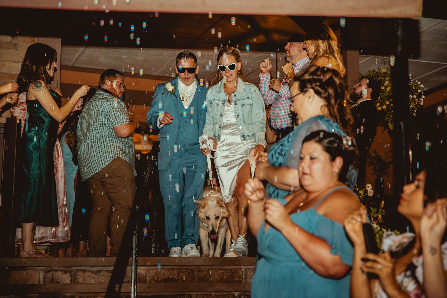 Guests celebrate on a dimly lit dance floor during an evening wedding reception.