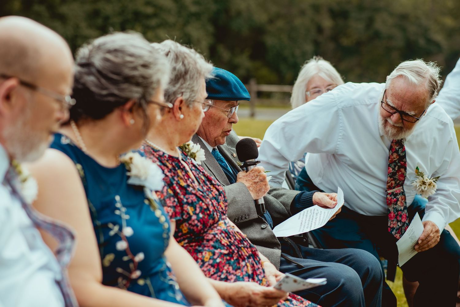 Wedding guests seated outdoors in casual attire watching a ceremony.