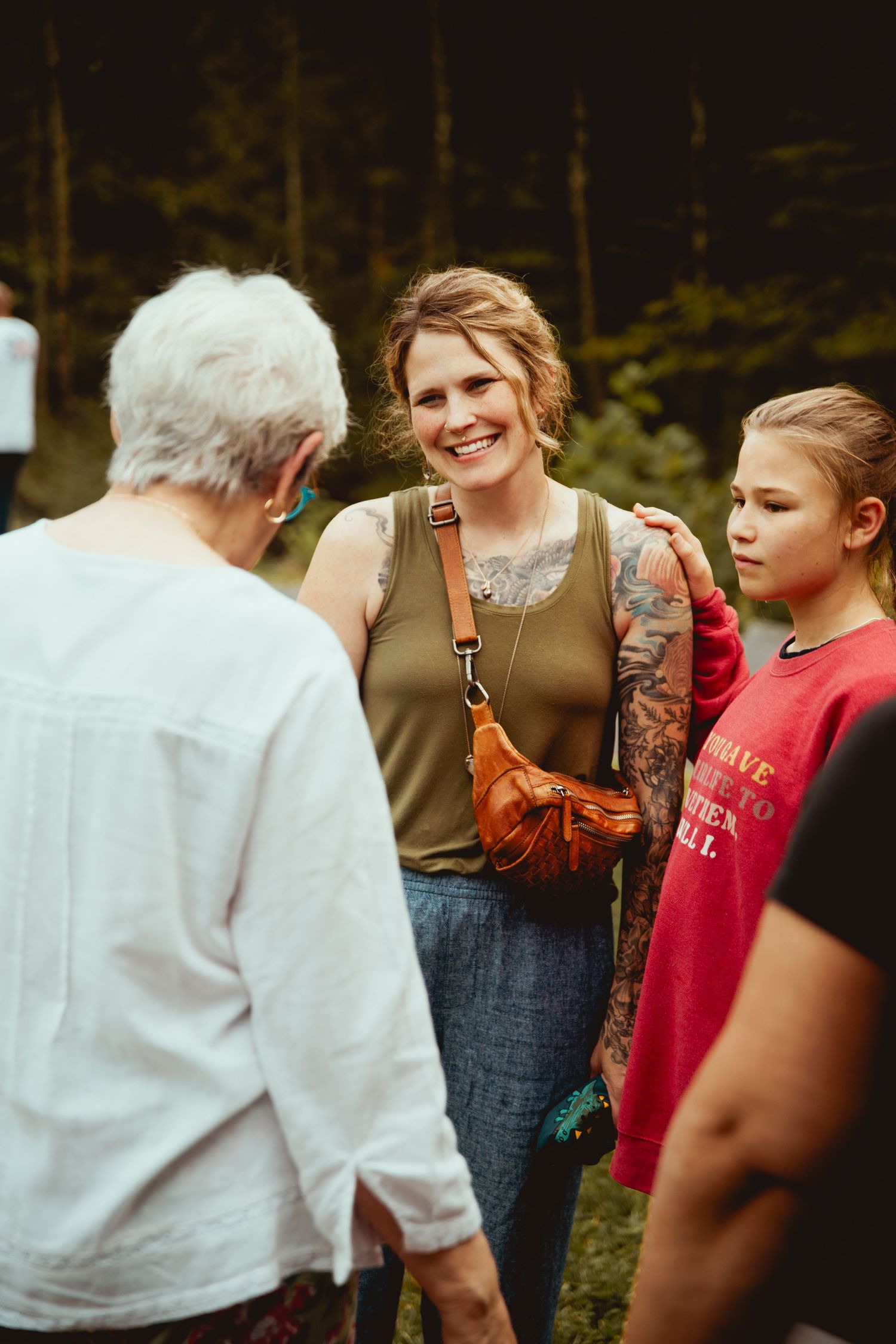 People enjoying a social gathering in a garden setting with natural lighting and casual attire.