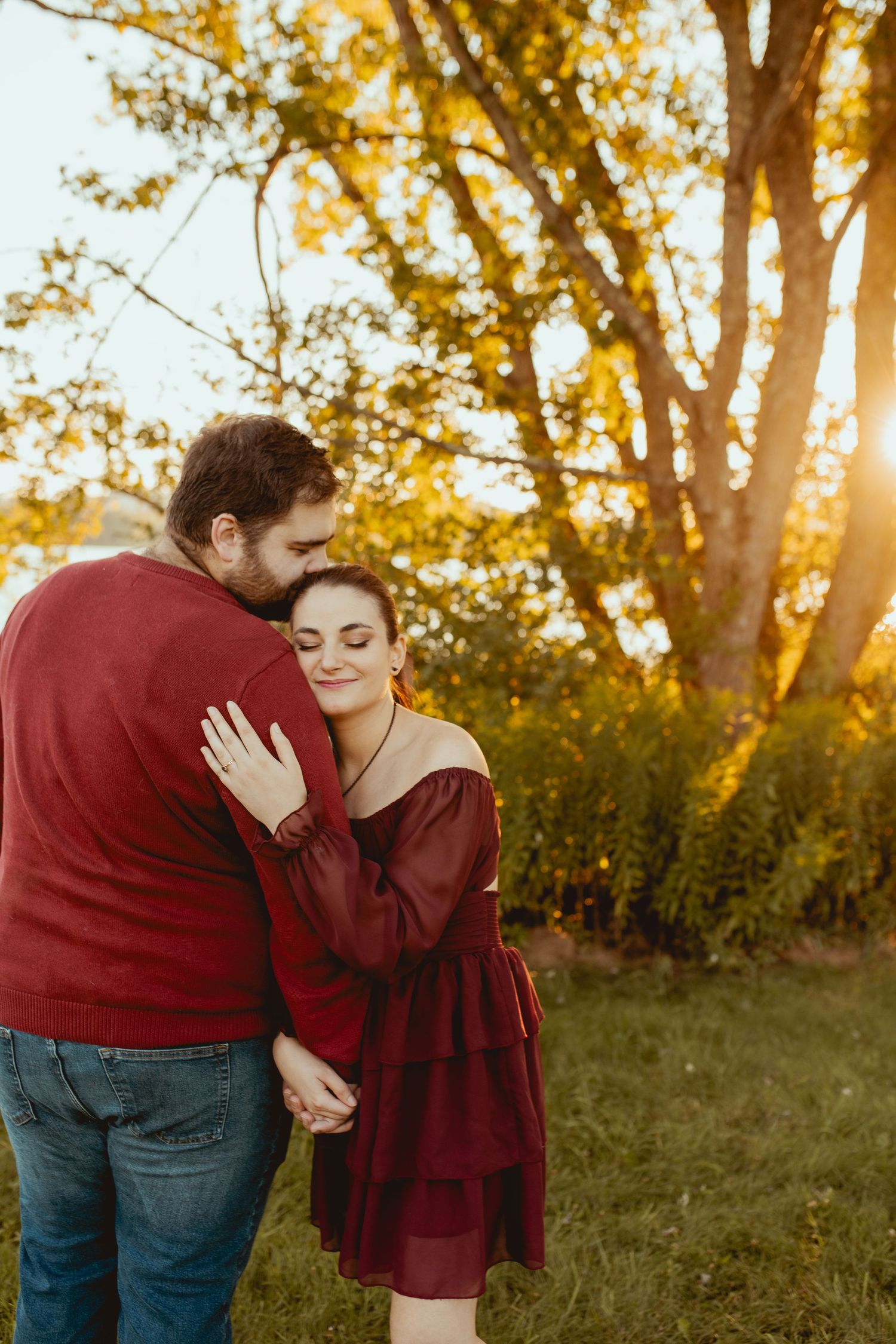 A couple shares tender moments in a romantic outdoor photoshoot at golden hour with autumn trees in the background.