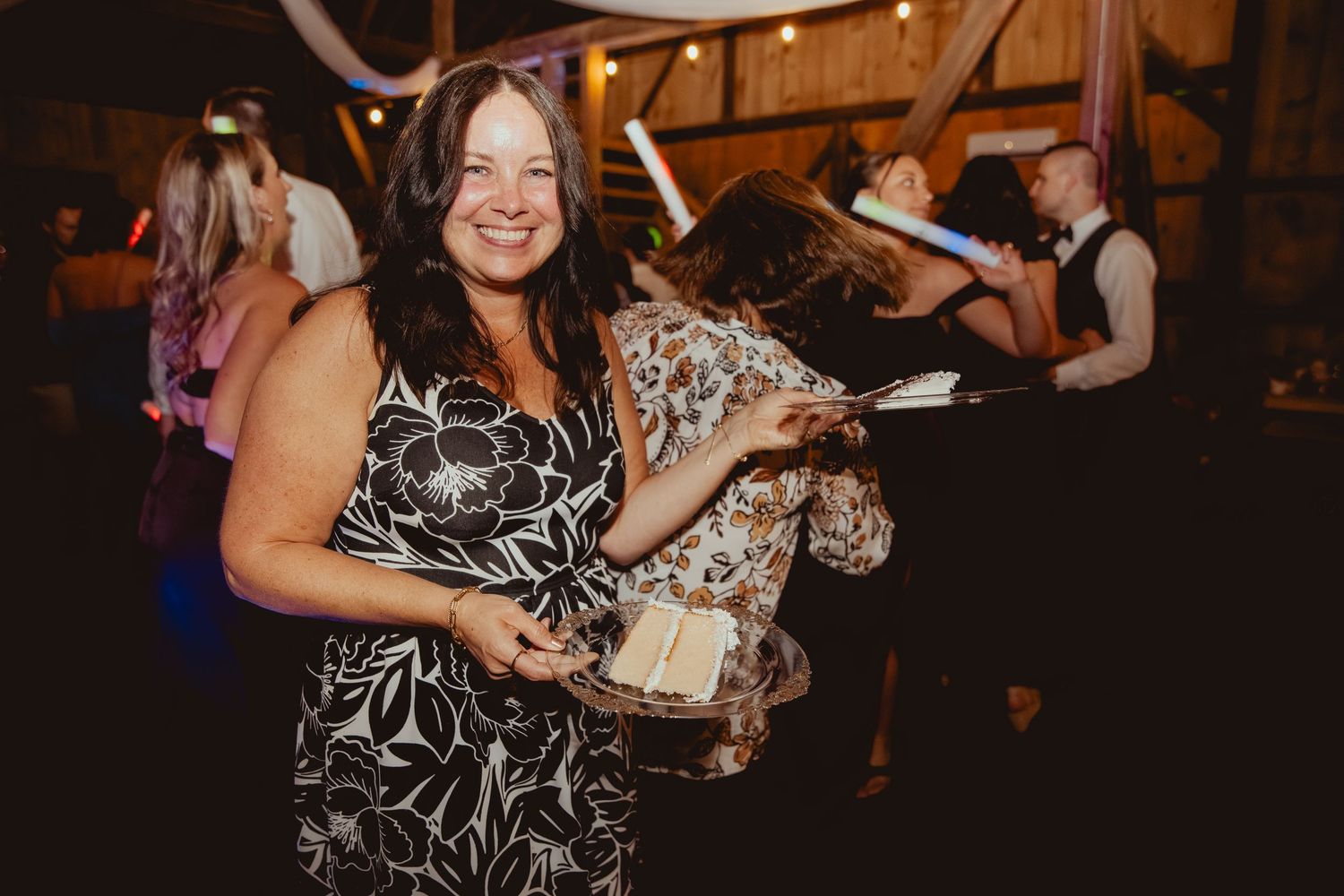 Wedding reception guests dancing and celebrating in a dimly lit venue.