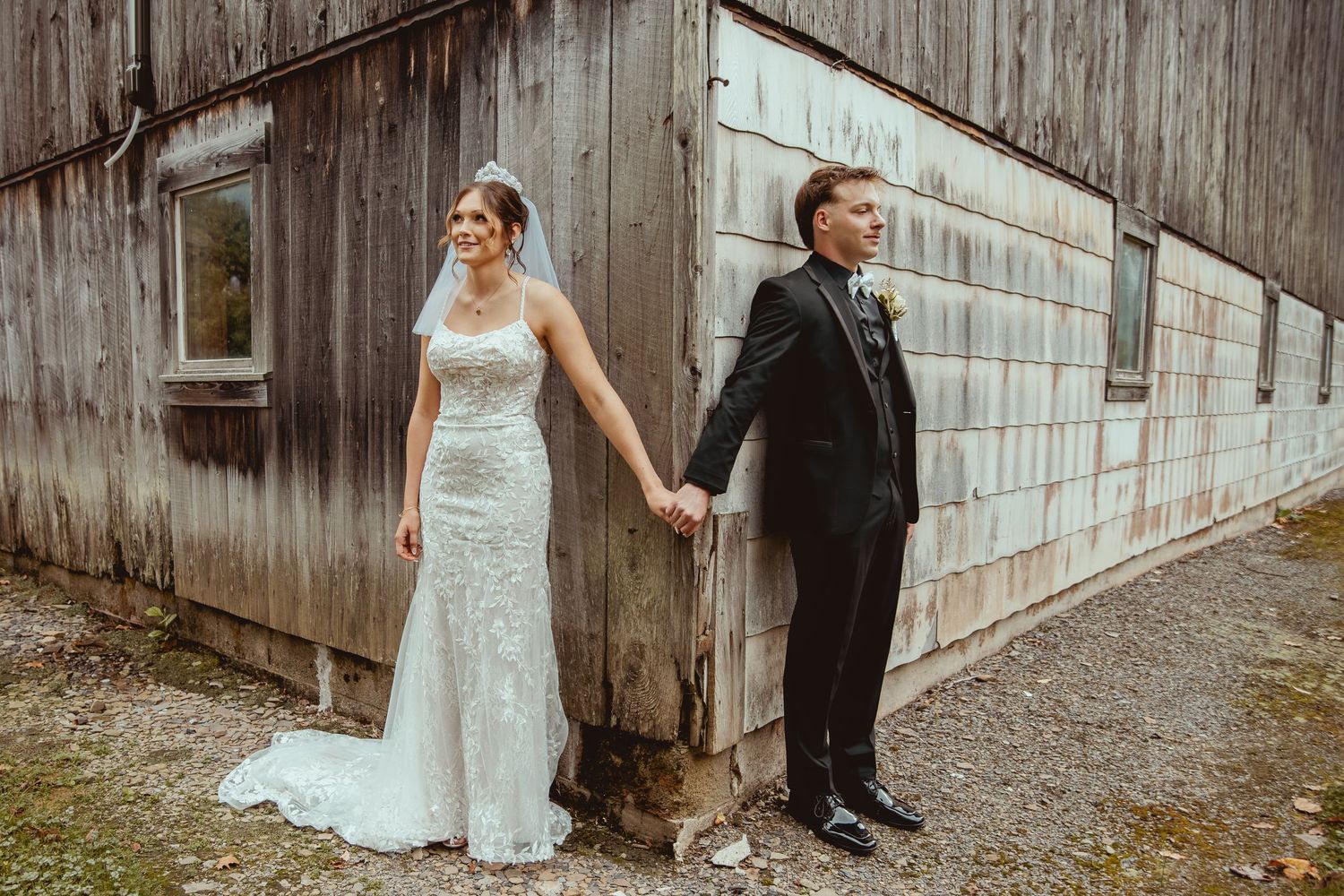 Romantic wedding photos taken against weathered wooden barn wall.