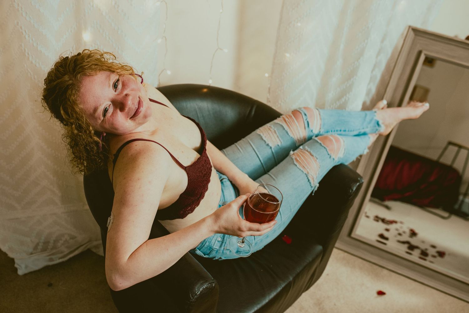 A person in a blue tank top lies on a black vinyl record while laughing and posing playfully.