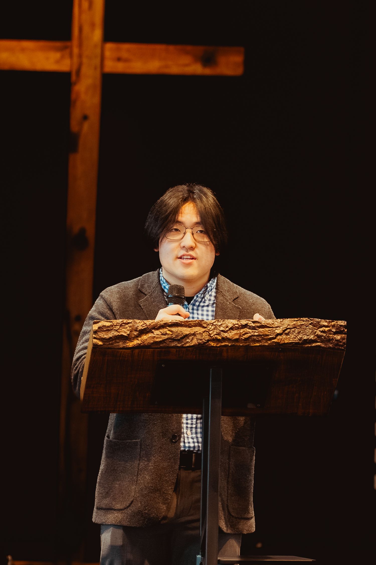 A wooden podium stands on stage against a dark background during a presentation.