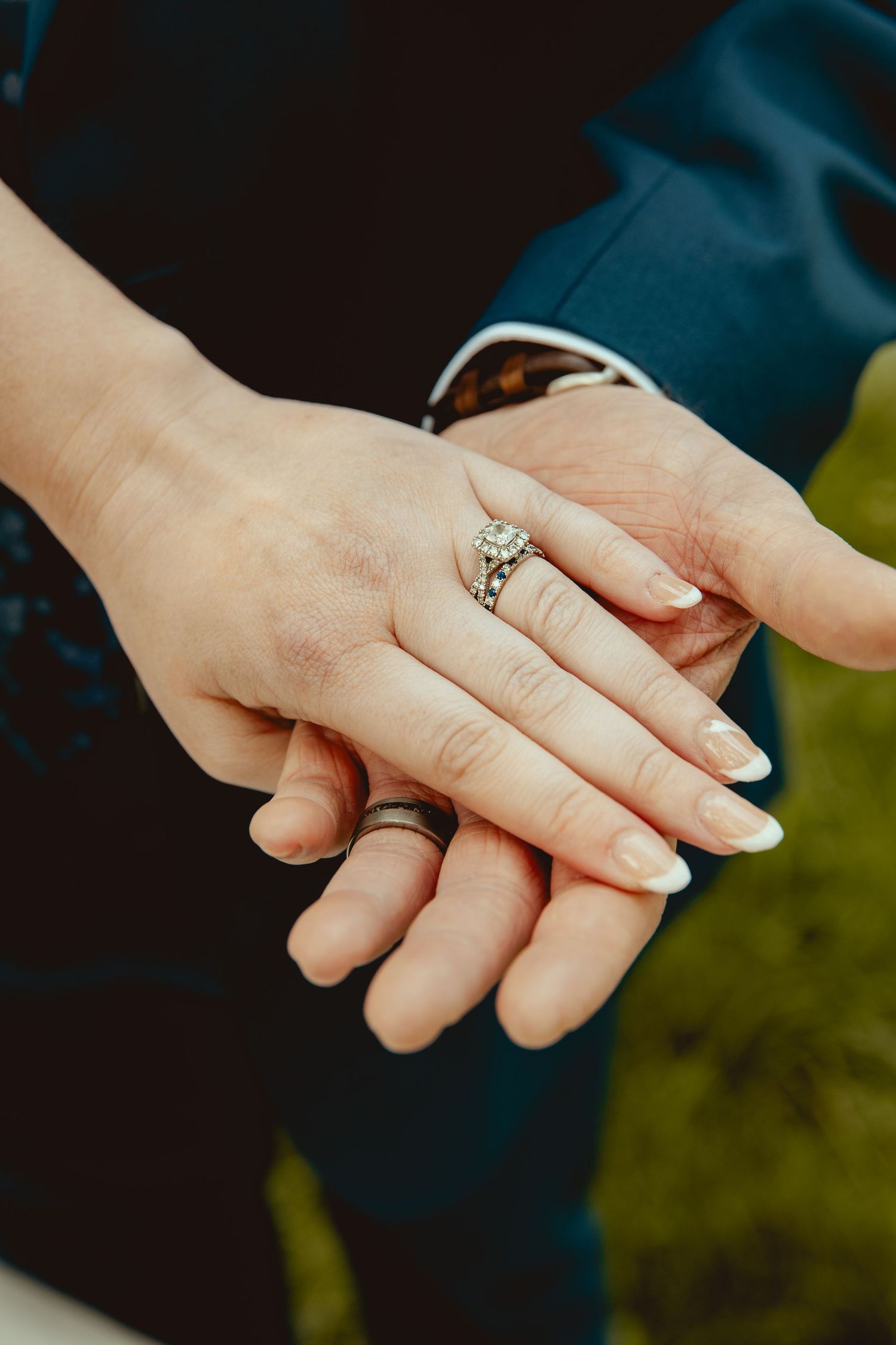 Close-up of newlyweds hands showing diamond engagement ring and wedding bands after ceremony.