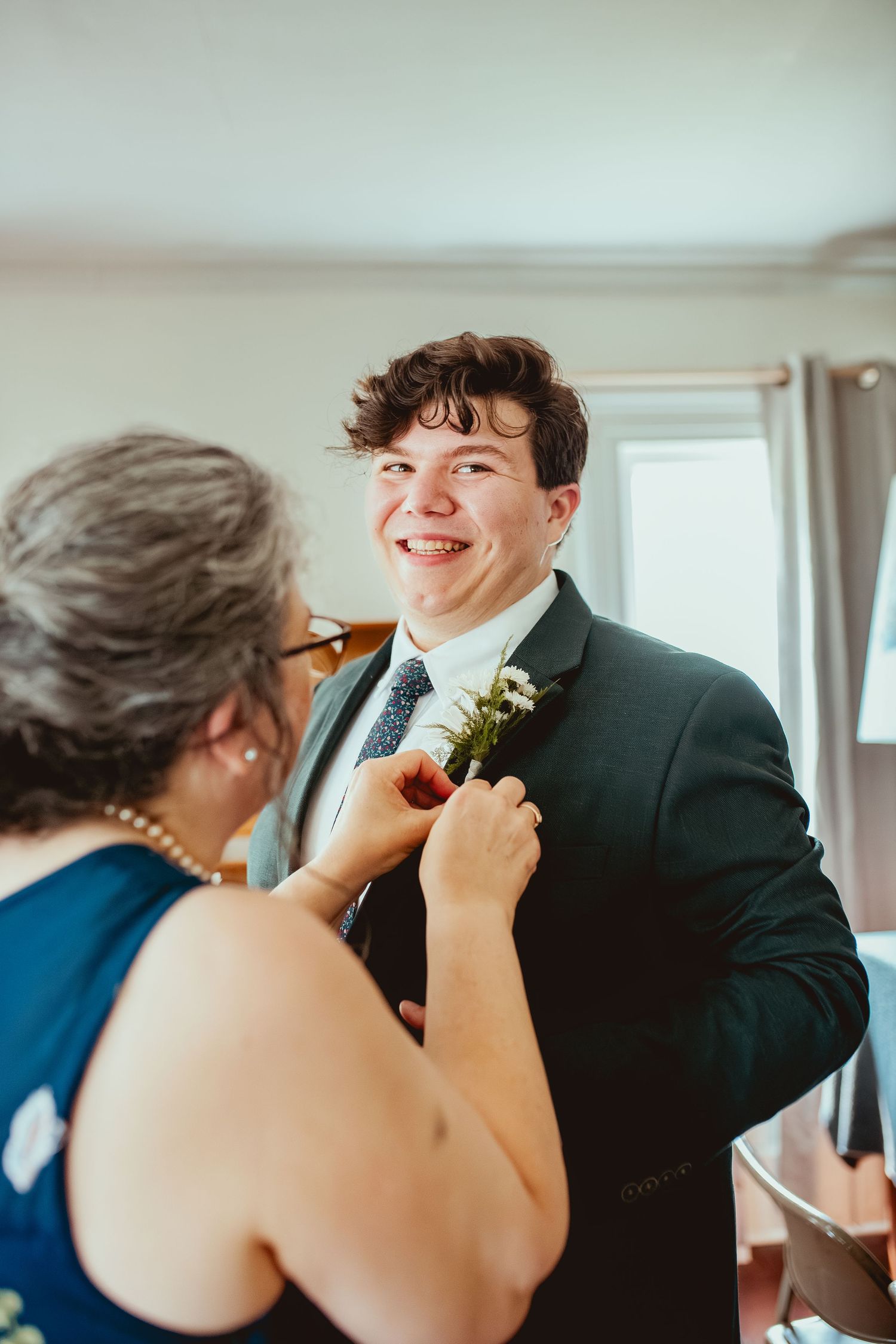 A touching moment between a mother and son as she adjusts his boutonniere before a formal event.