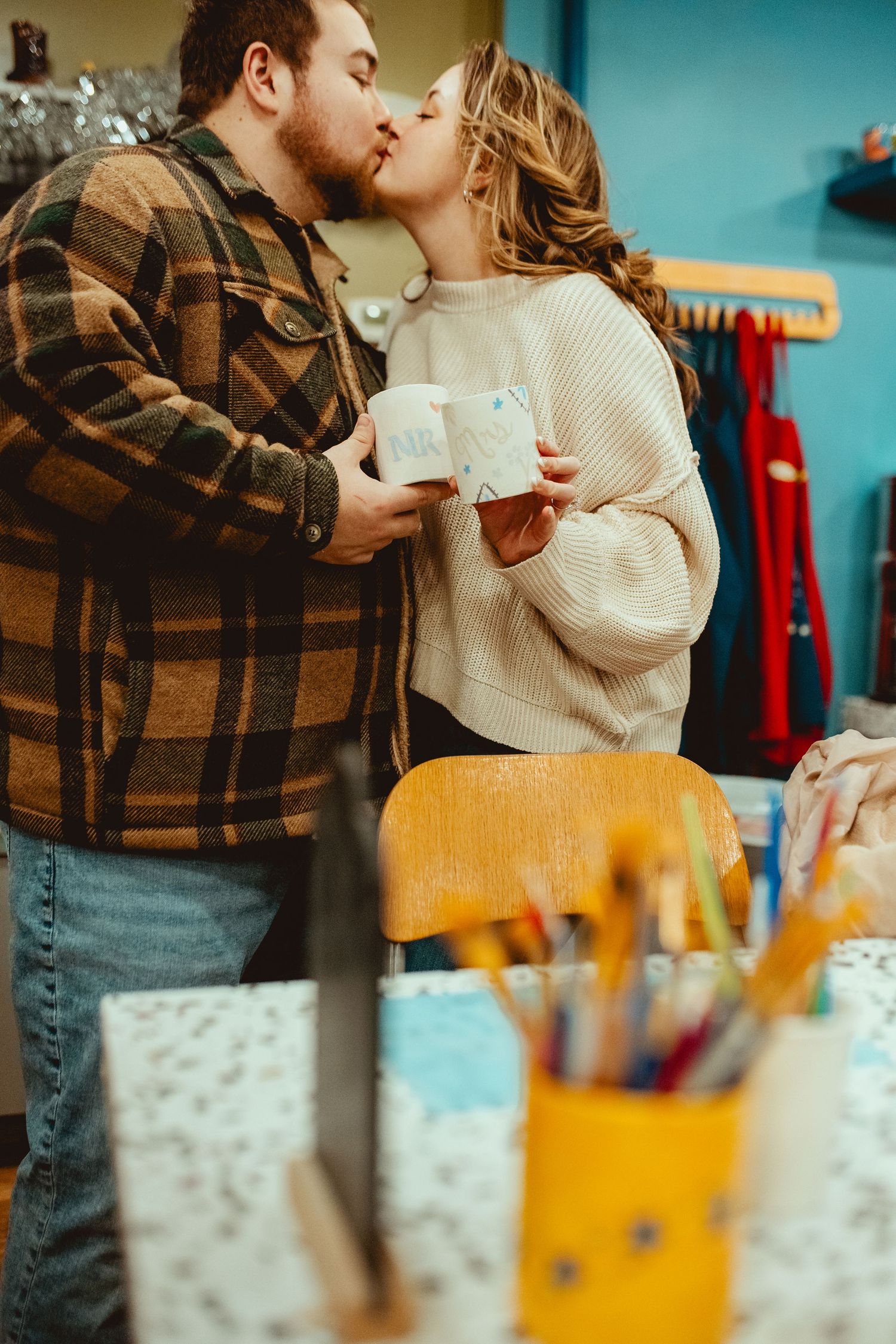 A romantic couple shares an intimate moment in a casual indoor setting with colorful decor in the background.