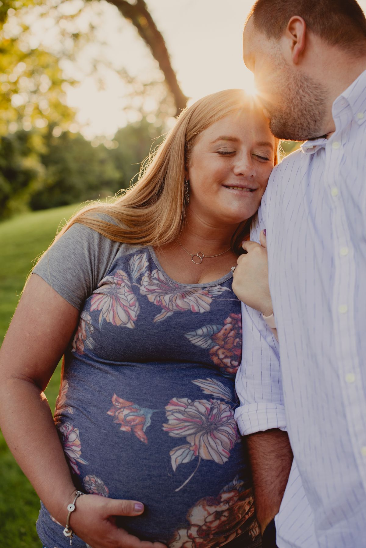Romantic couple embraces in a sun-drenched outdoor setting with golden light filtering through trees.