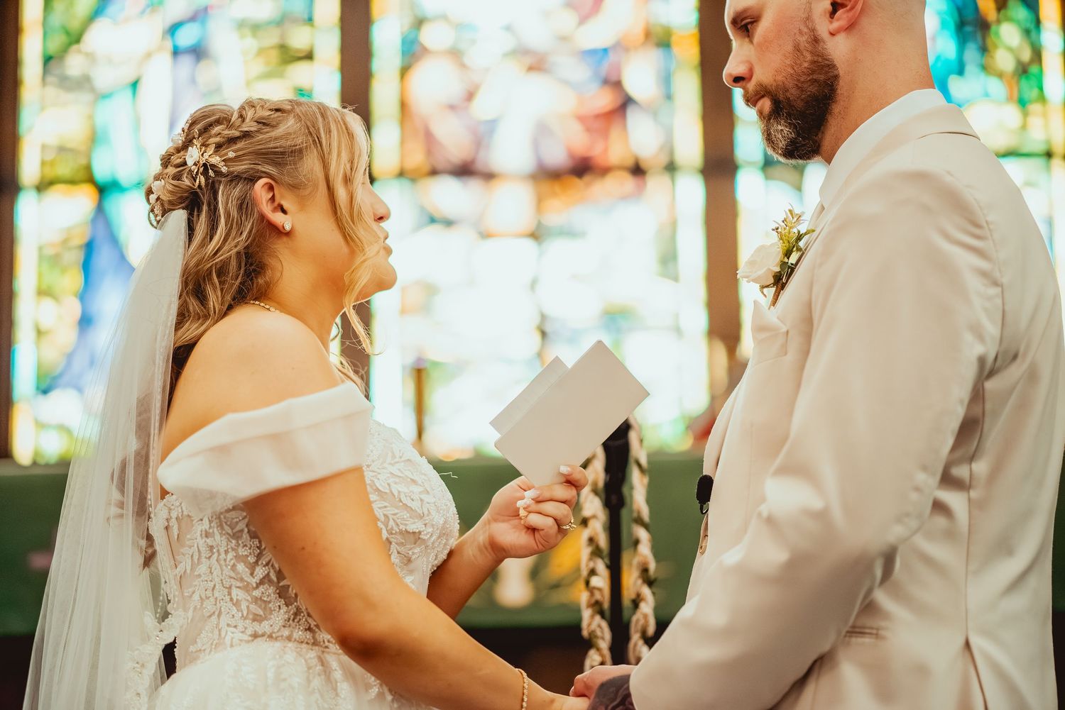 Bride and groom share a romantic first dance together at their wedding reception with stained glass windows in background.