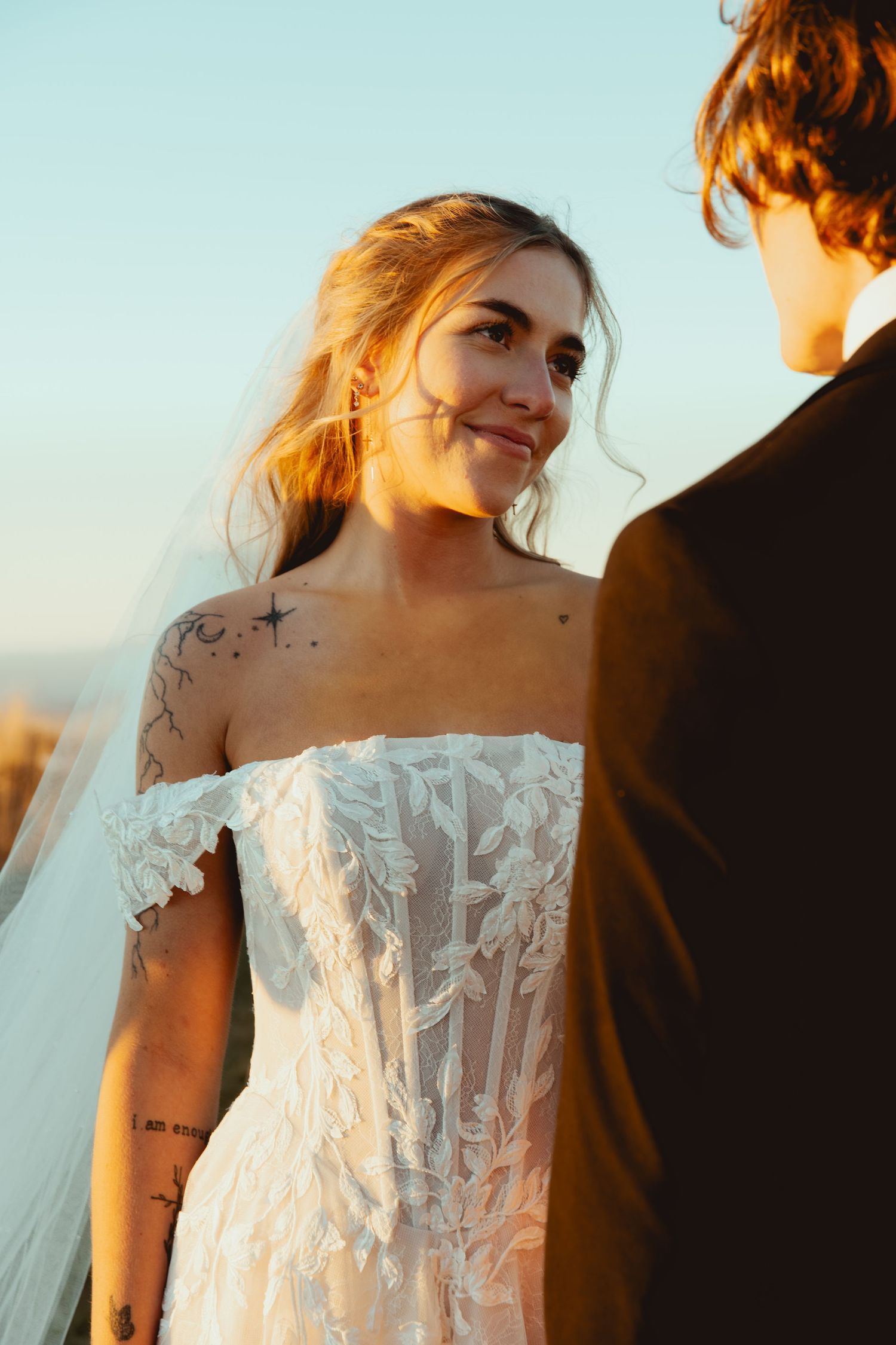 Close-up of bride in detailed lace wedding dress during golden hour.