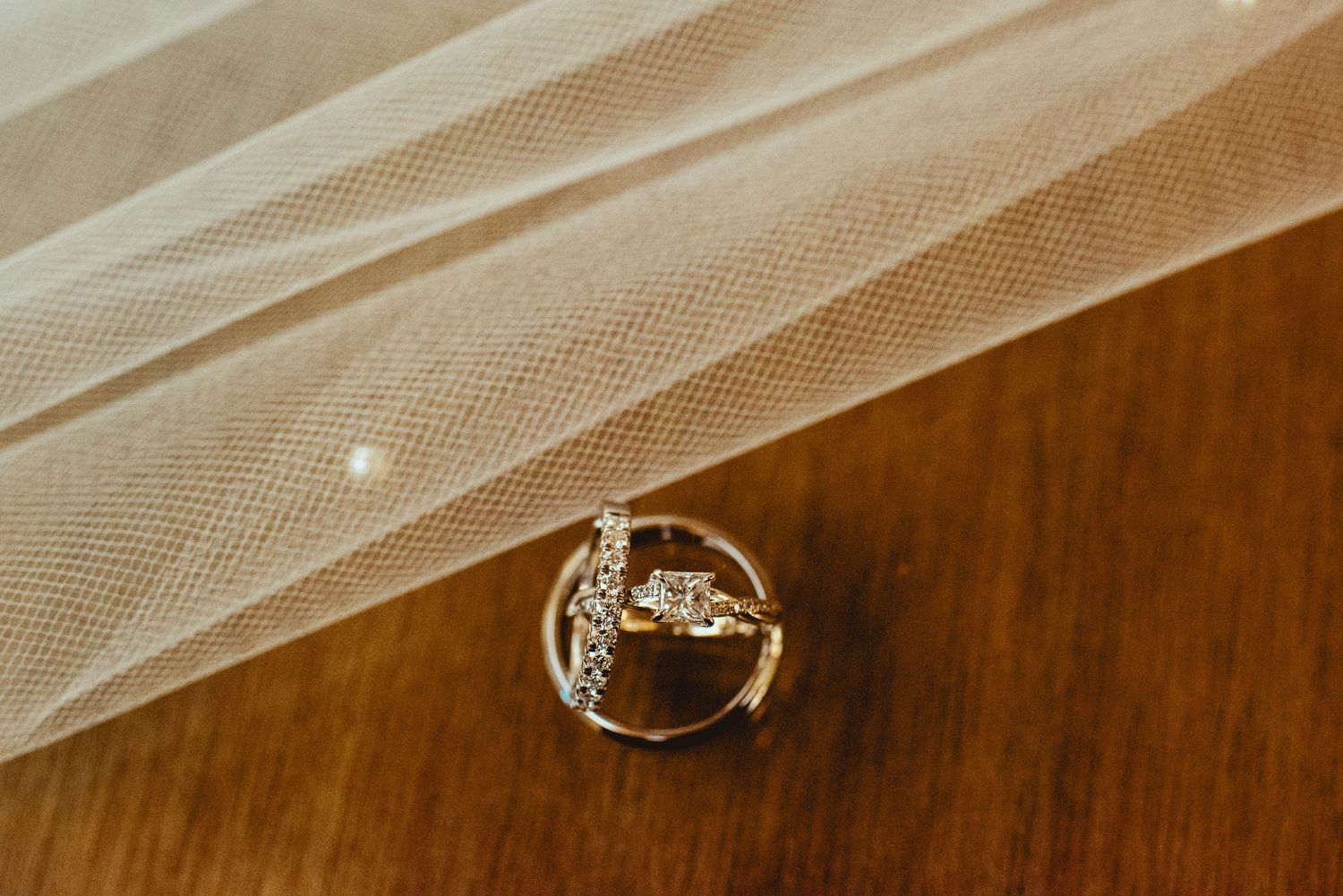 Close-up detail shot of elegant wedding rings on a wooden surface.