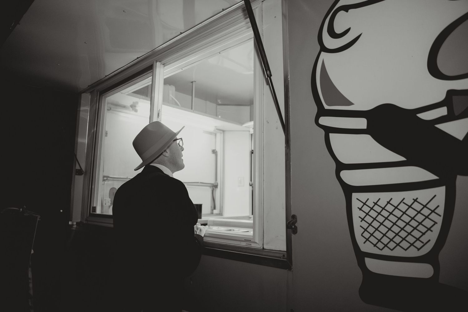 Silhouette of a person looking through a window with an ice cream cone decal visible.
