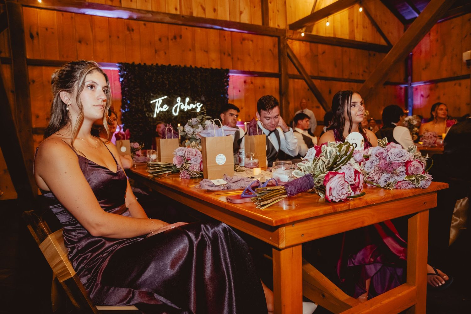 Reception tables set up inside a rustic wooden barn with purple decor accents.