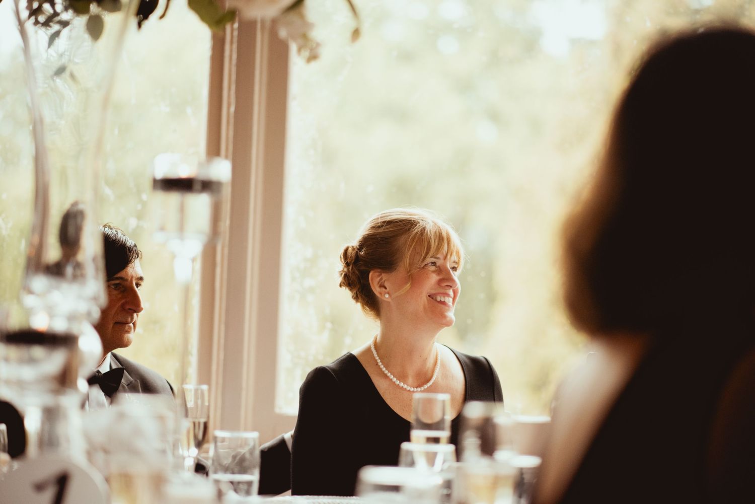 A bride and groom share a joyful laugh during their wedding celebration in a bright indoor venue.