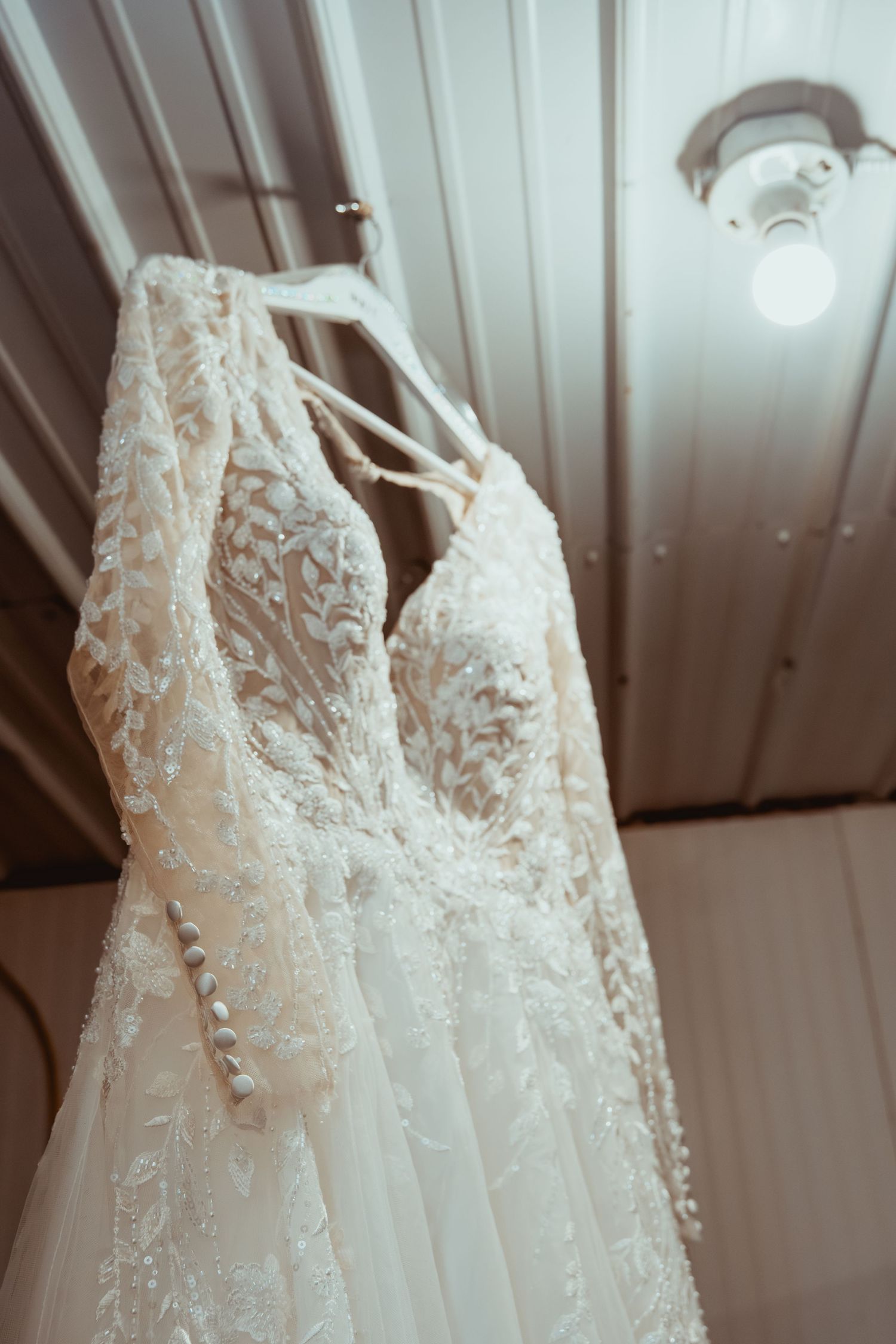 Close-up view of delicate white lace wedding dress bodices hanging in a row with intricate floral embellishments.