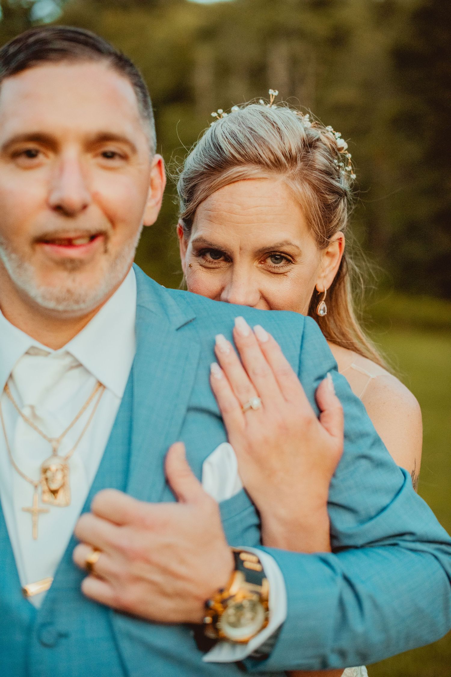 Close-up wedding photo showing turquoise suit and white dress details.