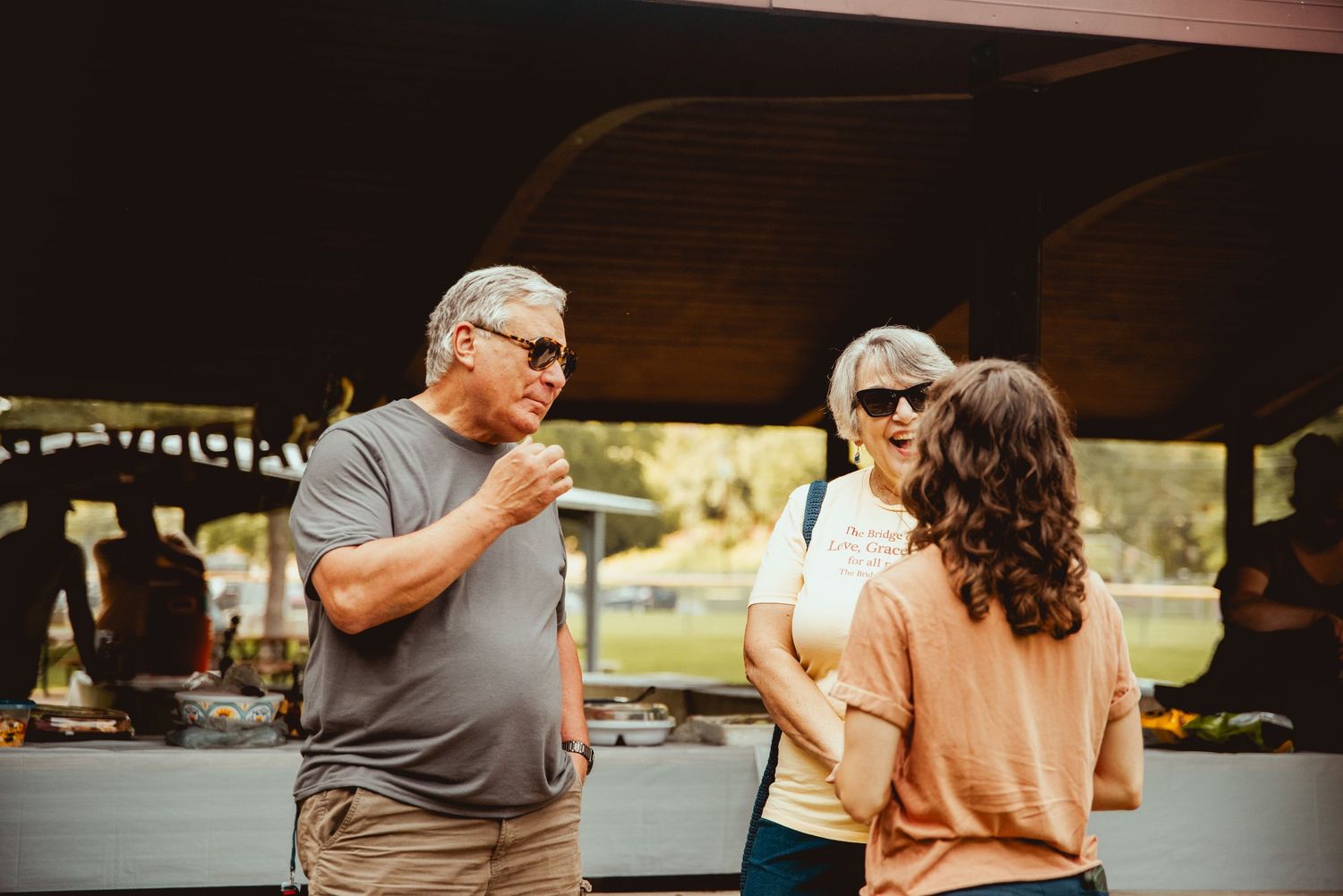 A group of friends enjoying drinks and conversation at an outdoor patio table on a sunny afternoon.