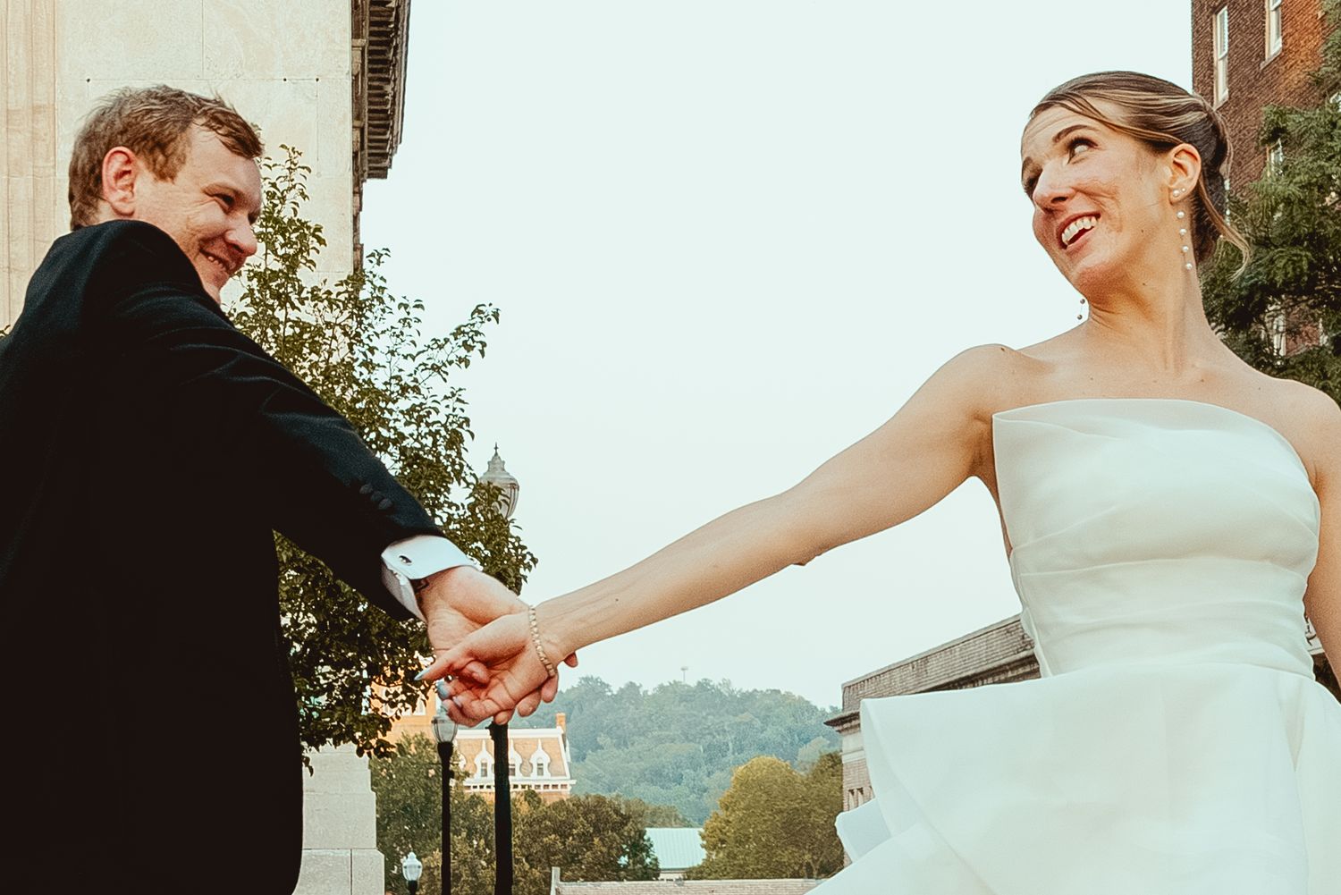 A couple shares a joyful moment dancing together outdoors on their wedding day.