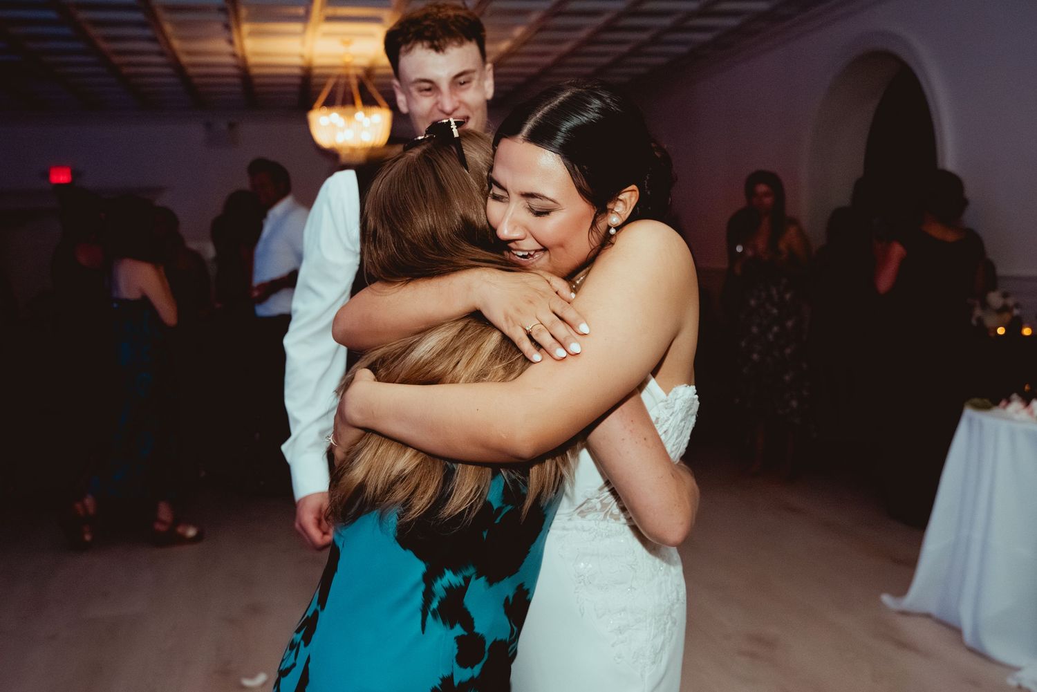 People dancing together at a dimly lit wedding reception venue with warm lighting and romantic atmosphere.