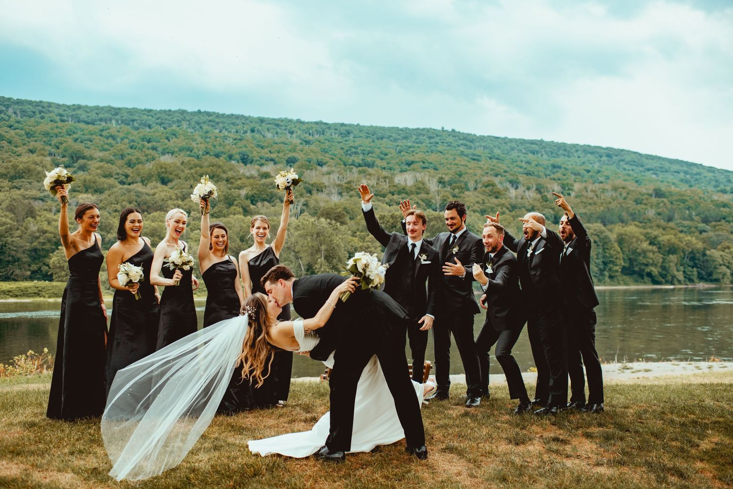 Wedding party posing dramatically against scenic mountain backdrop.
