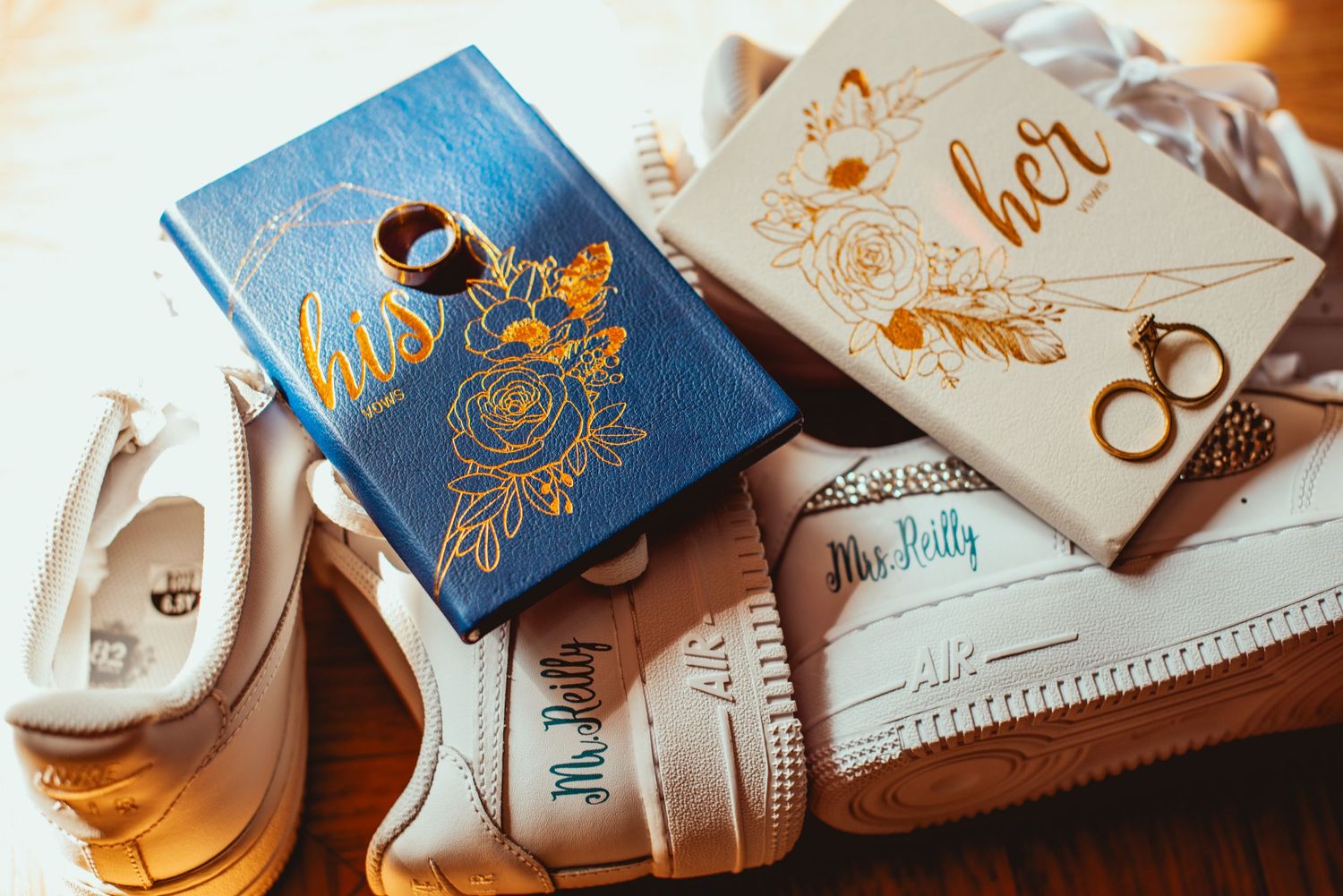 Elegant wedding invitations and stationery with gold foil details and calligraphy arranged on a wooden surface.