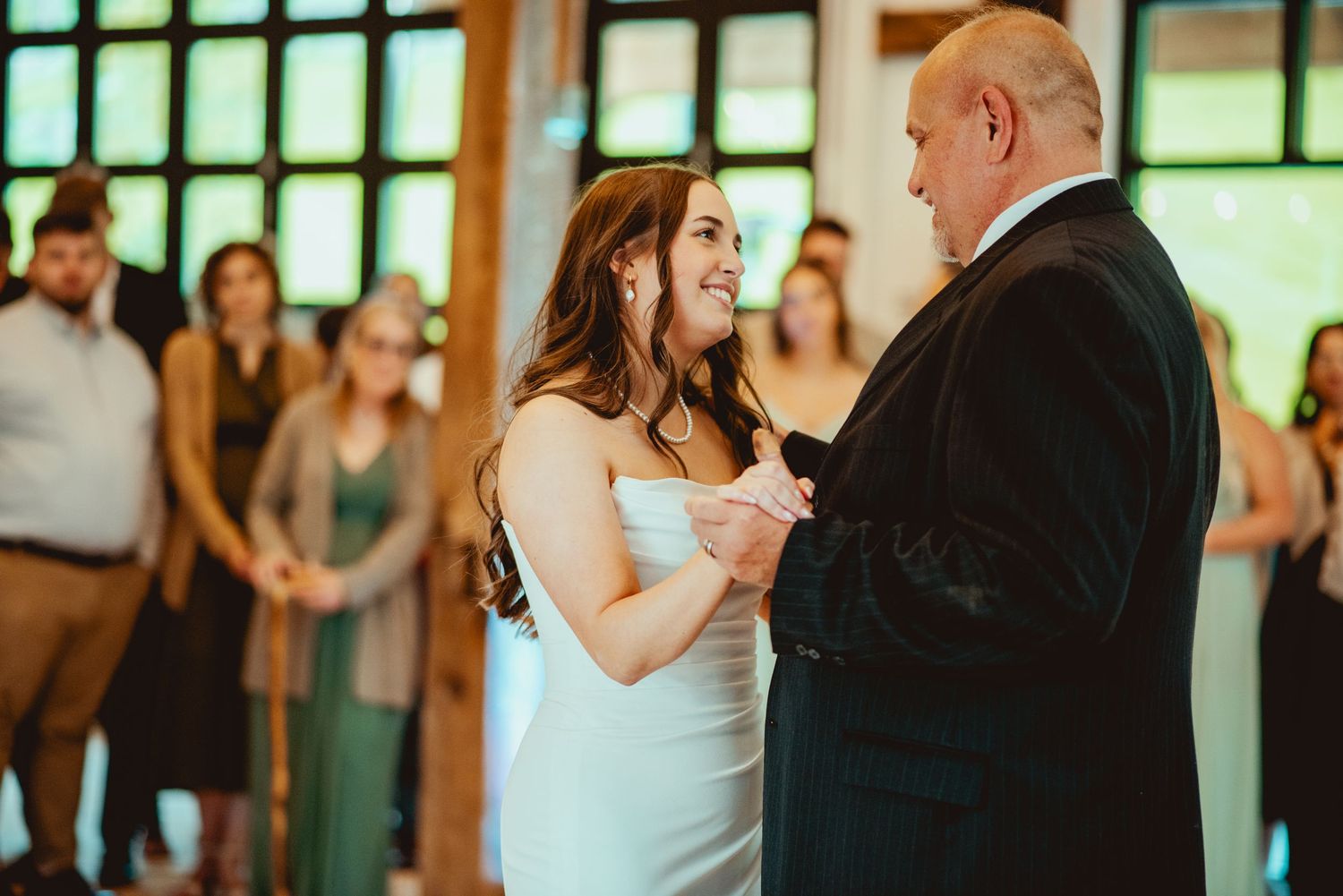 Couples dancing on a wooden dance floor in a rustic venue with natural lighting.
