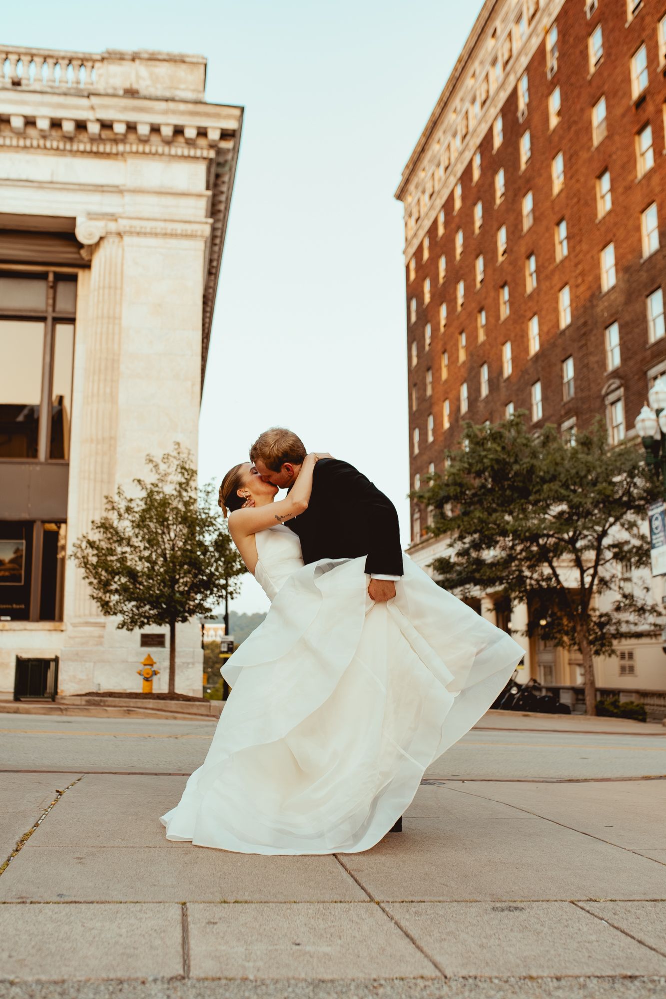 A series of wedding photos showing a couple dancing and embracing on a sidewalk near brick buildings.