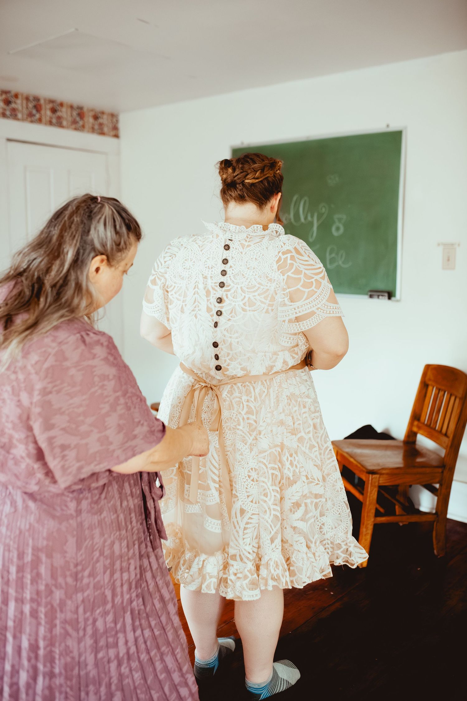 A sequence of four vintage-style photos showing two people in a classroom setting wearing white and pink dresses.