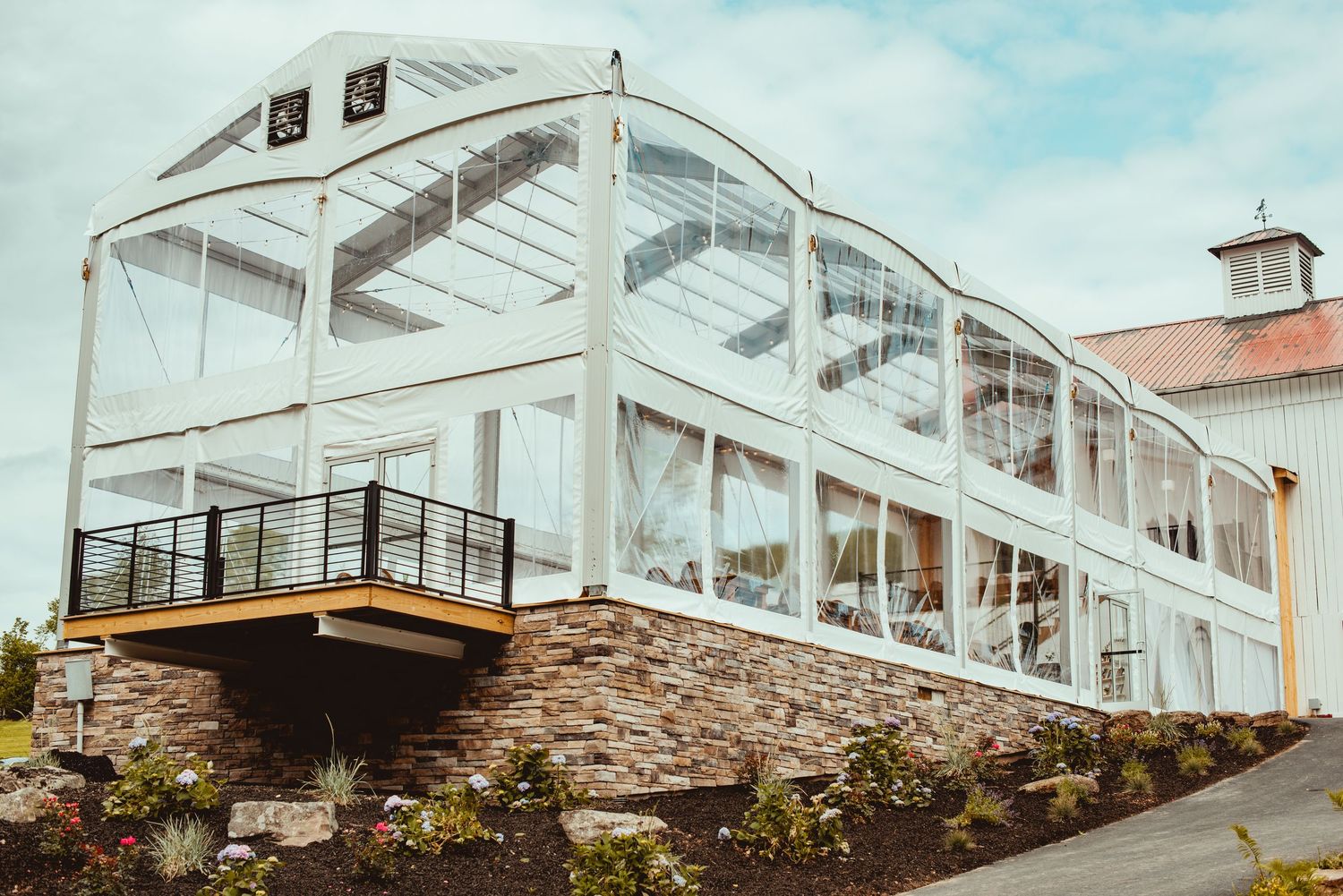 Modern glass conservatory with stone foundation and white trim architecture at wedding venue.
