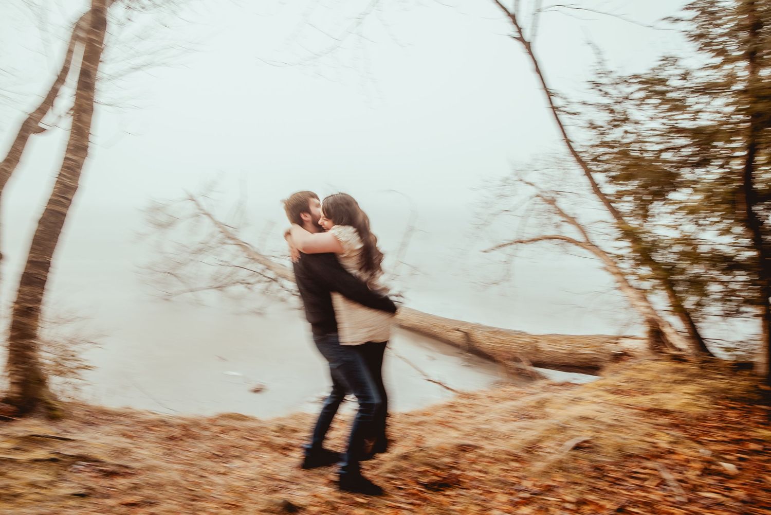 Two people dancing together in a romantic pose among autumn trees in a misty forest setting.