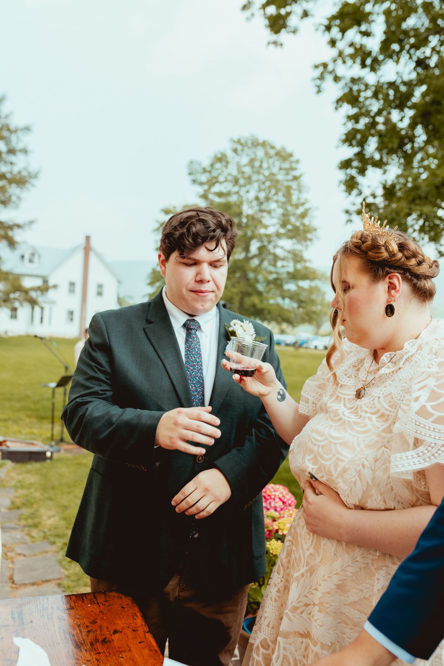 A couple shares drinks and laughter during their outdoor wedding celebration.