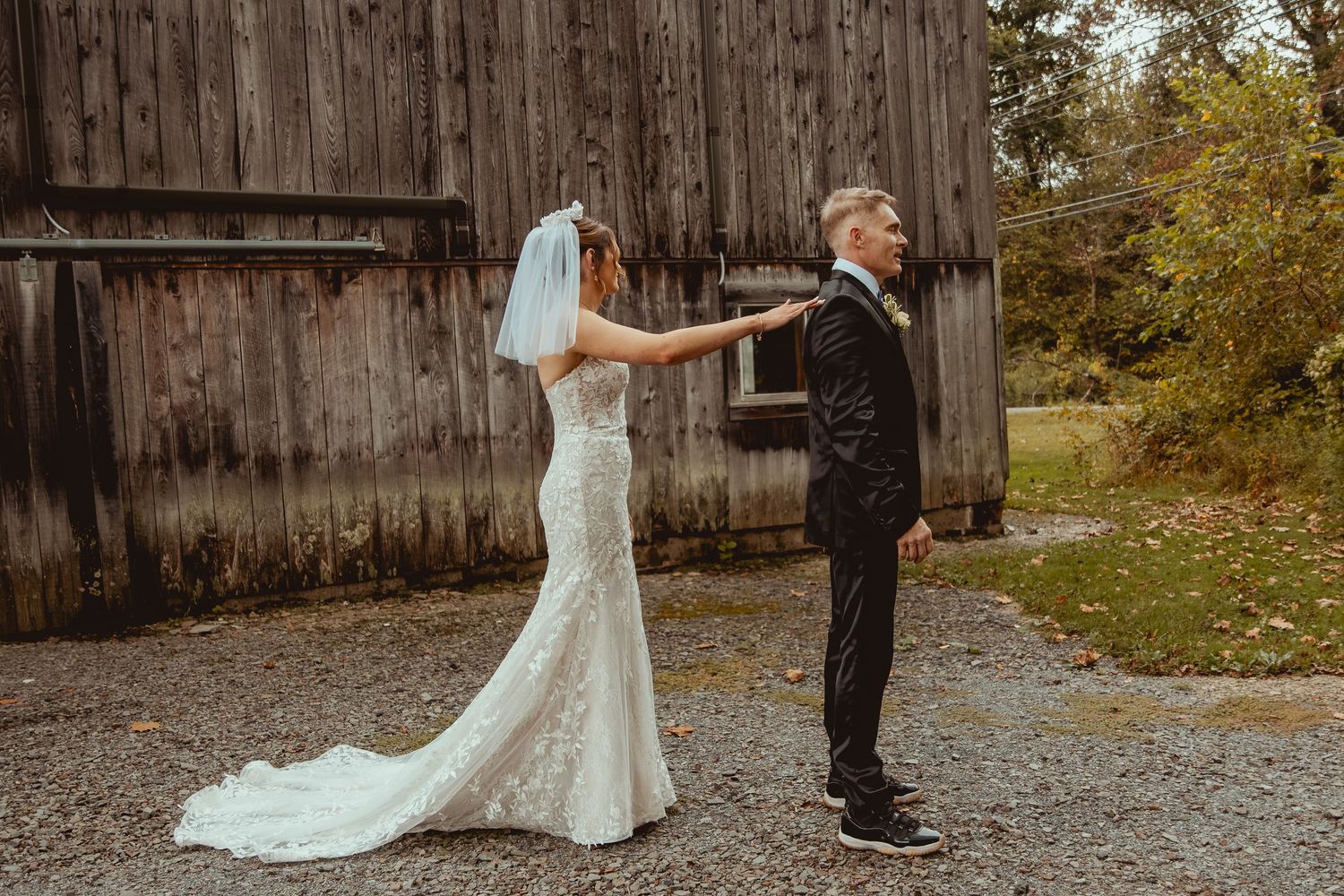 A couple shares an intimate moment in front of a rustic wooden barn during their wedding ceremony.