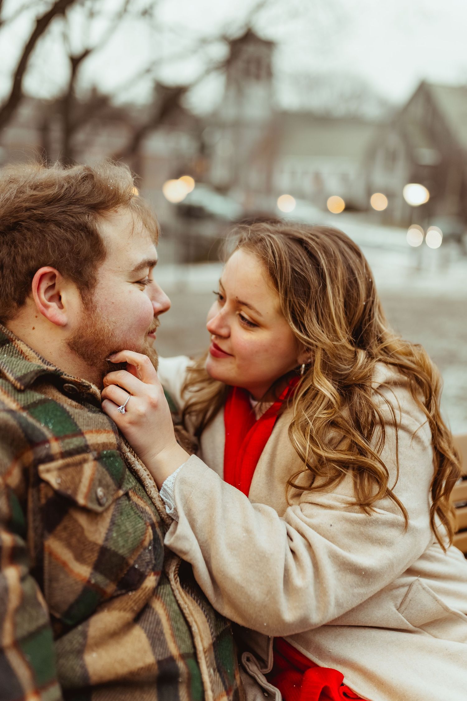 A romantic couple shares an intimate moment outdoors in winter clothing.