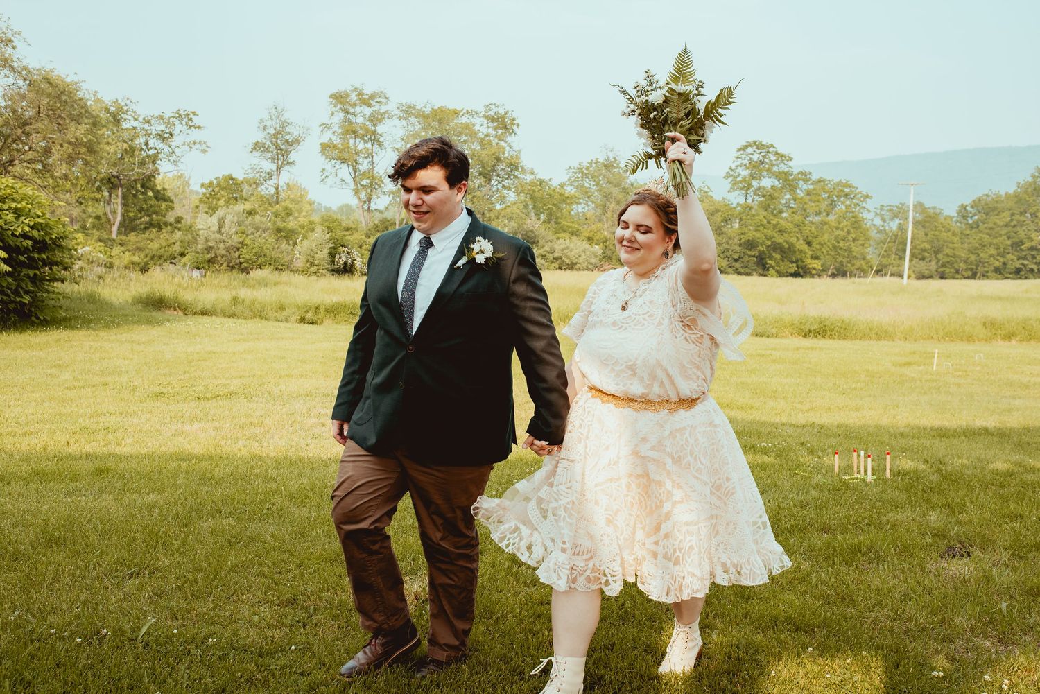 A couple shares romantic moments in a sunny outdoor setting during their wedding celebration.