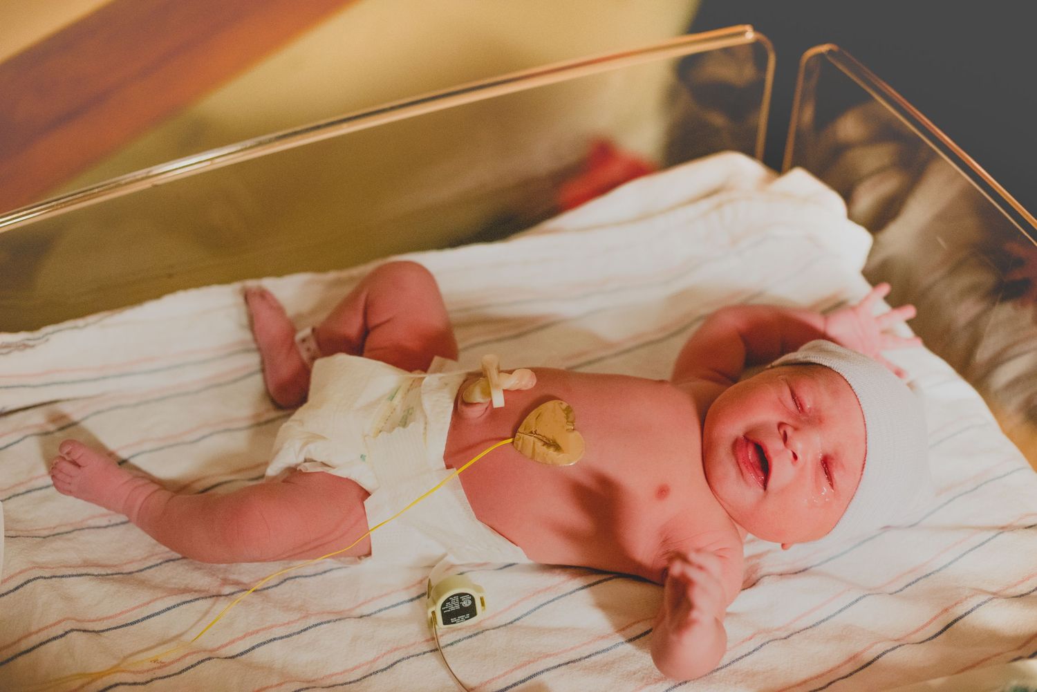 A series of seven images showing a newborn baby lying on white bedding and expressing different emotions.