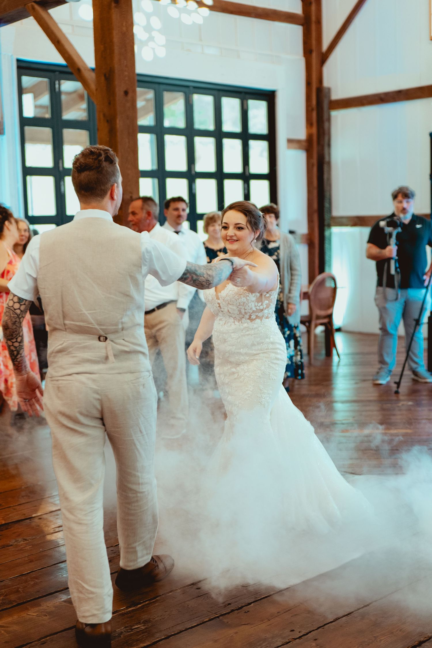Bride and groom share first dance surrounded by dramatic fog in rustic barn reception venue.