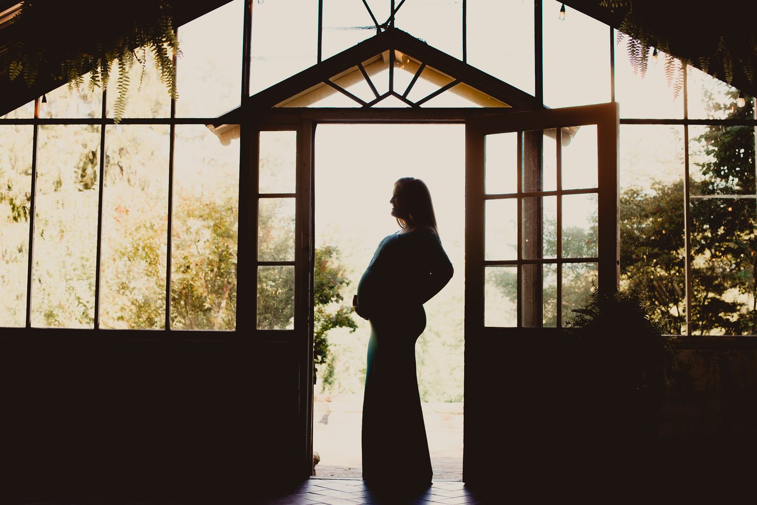 Silhouettes of people stand in front of large windows at sunset creating a dramatic backlit scene.