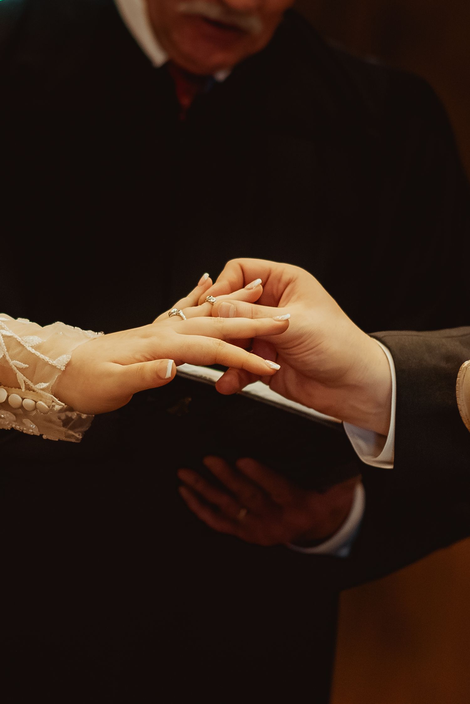 Business professionals exchanging business cards in a formal setting with hands shown against dark background.
